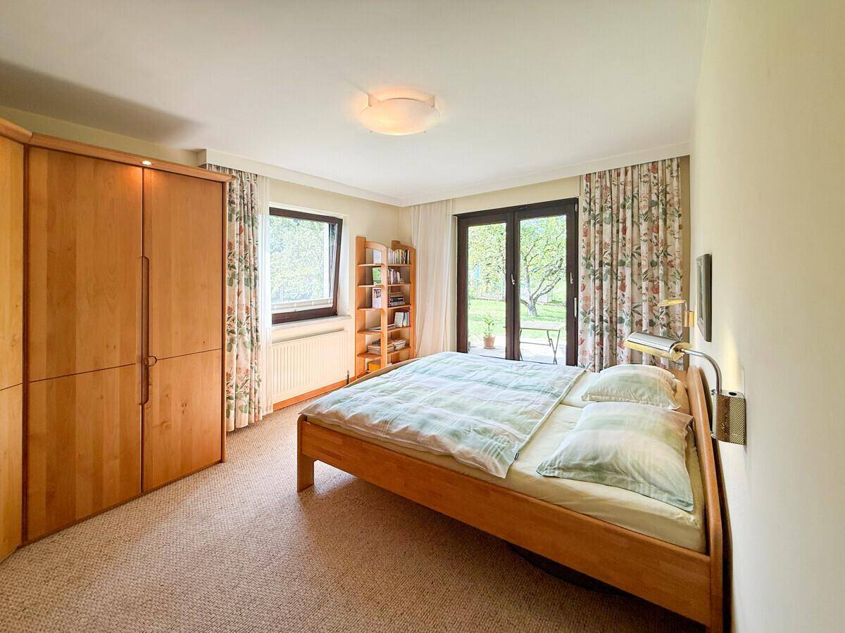 Helles Schlafzimmer mit Teppichboden und direktem Zugang zum Garten.