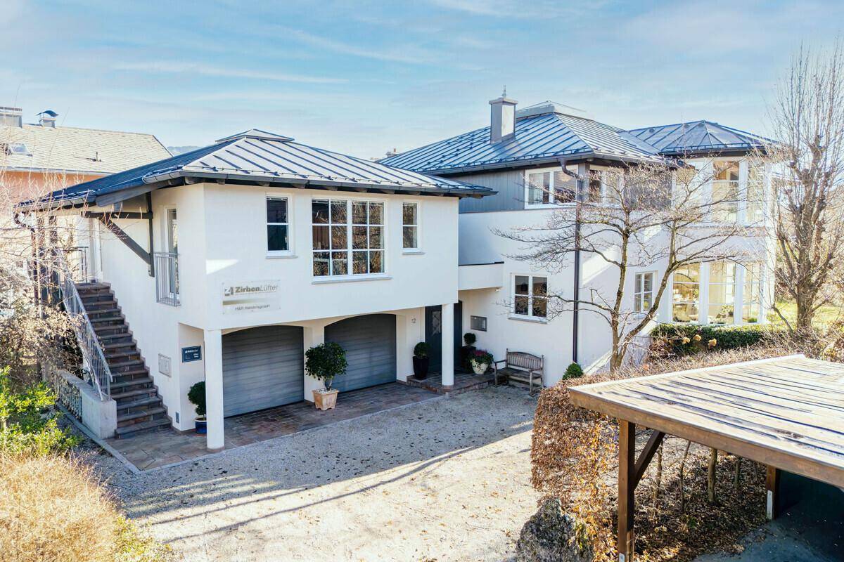 Großzügiges Wohnhaus mit Doppelgarage, Carport und moderner Architektur unter blauem Himmel.