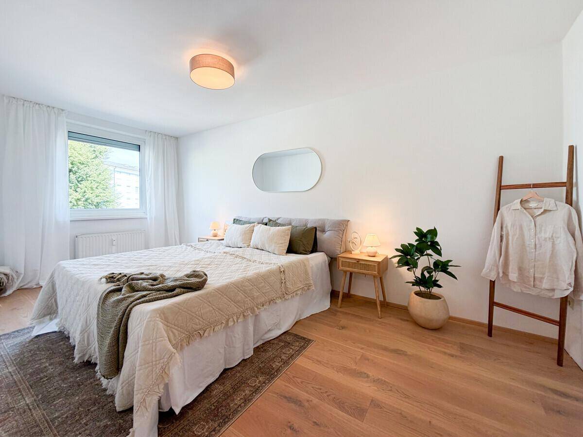 Ruhiges Schlafzimmer mit Holzboden, Doppelbett und schlichter, moderner Einrichtung.