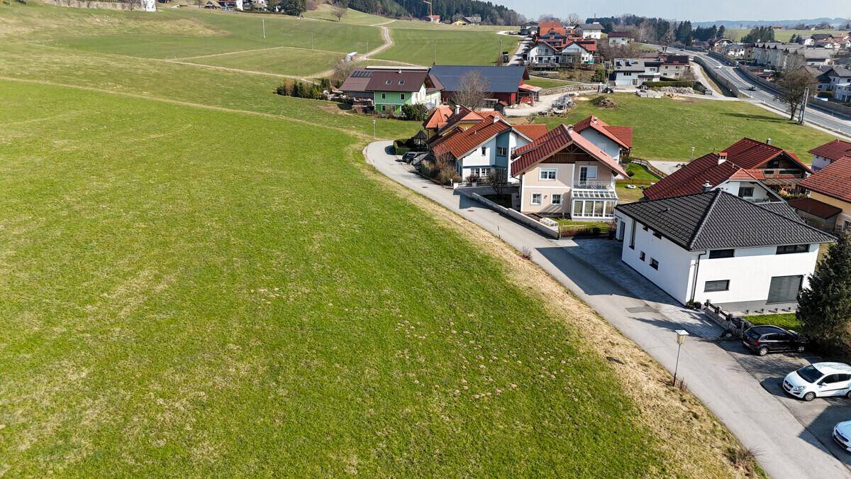 Luftaufnahme einer Wohnsiedlung am Rande grüner Felder mit verschiedenen Haustypen.