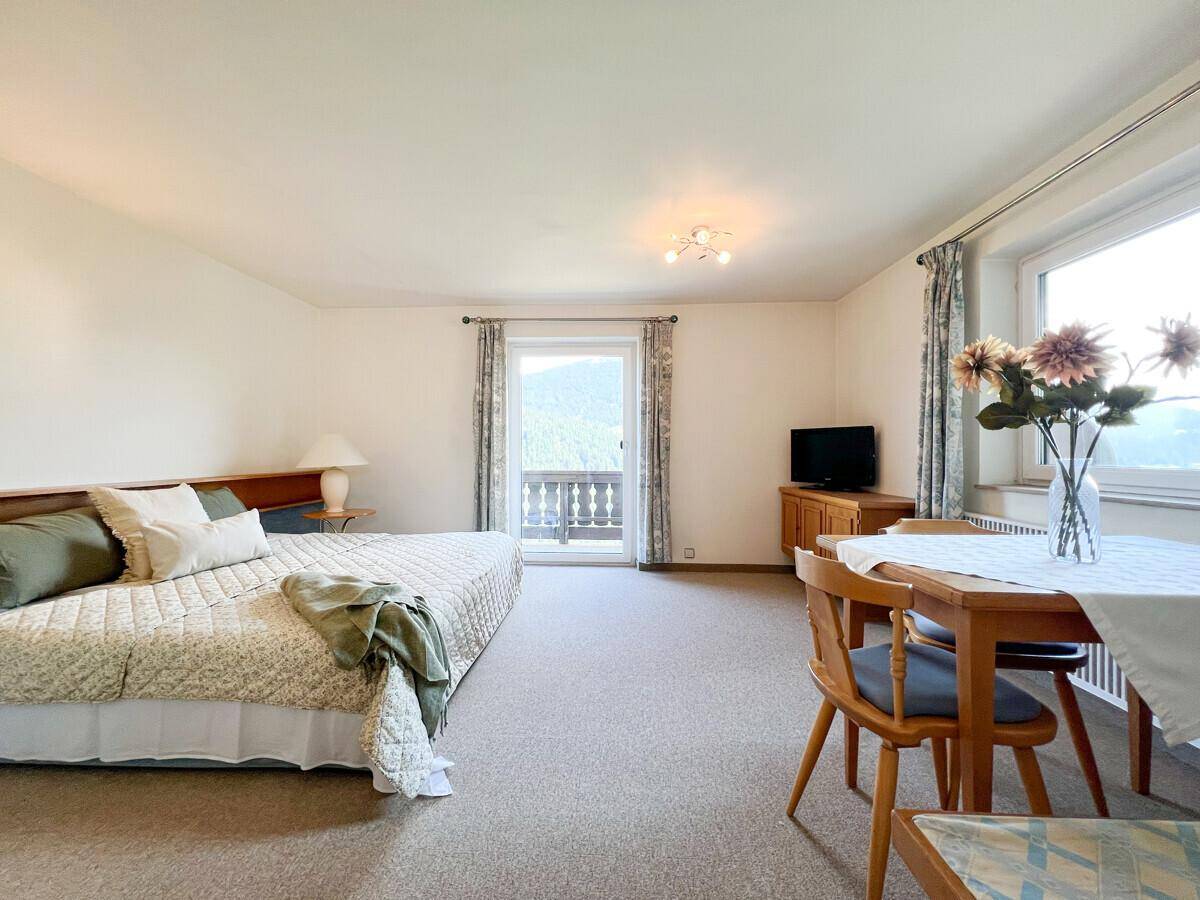 Geräumiges Schlafzimmer mit Teppichboden, Esstisch und direktem Zugang zu einem Balkon.