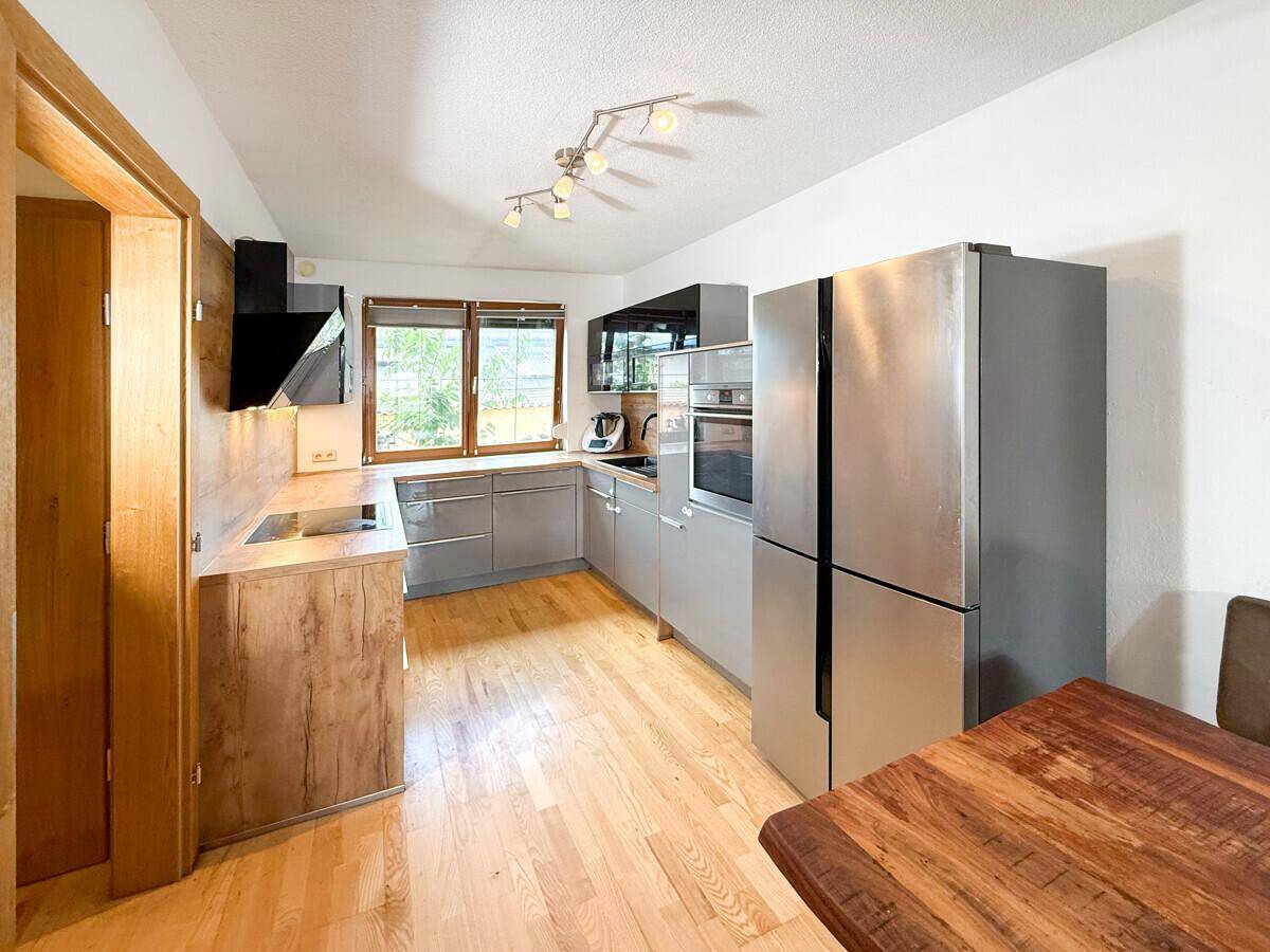 Moderne Küche mit grauen und holzfarbenen Schränken, ausgestattet mit Geräten.