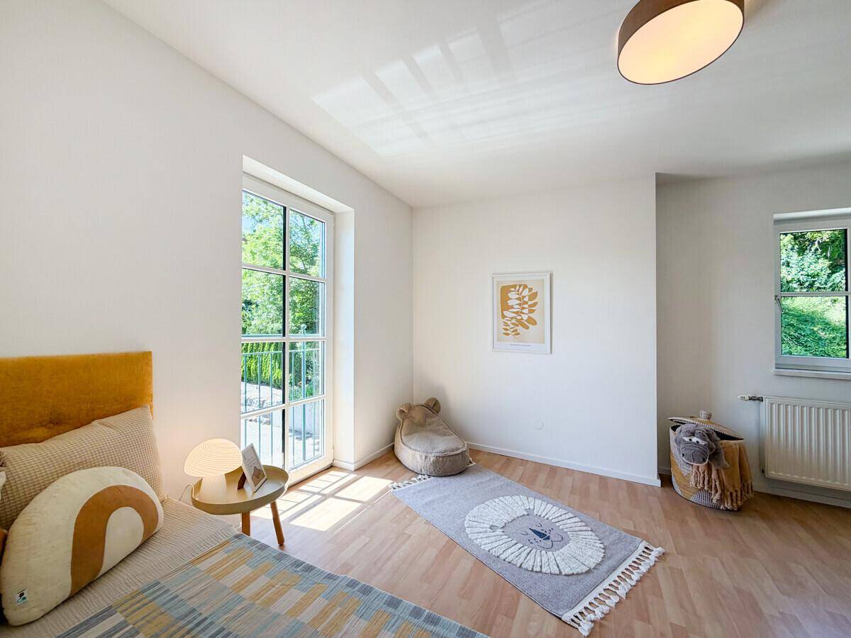 Freundliches Kinderzimmer mit Laminatboden, Einzelbett und Blick ins Grüne.