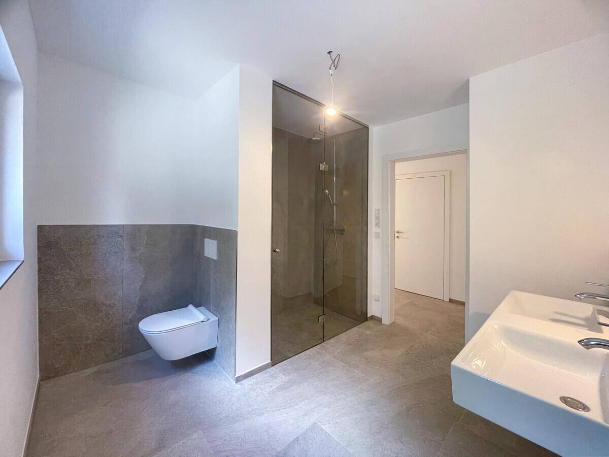 Modernes Badezimmer mit begehbarer Dusche, Wand-WC und Doppelwaschbecken.