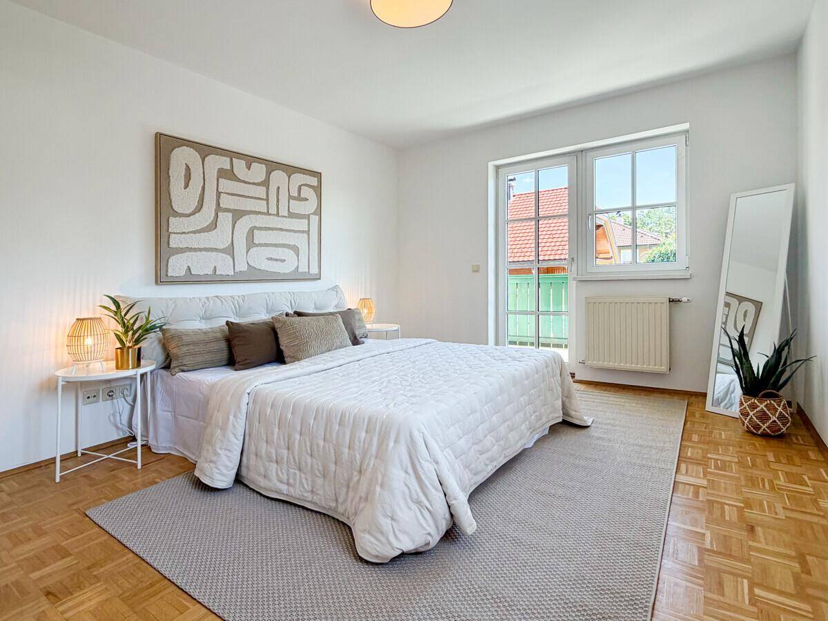 Geräumiges Schlafzimmer mit Parkettboden, Doppelbett und viel Tageslicht.