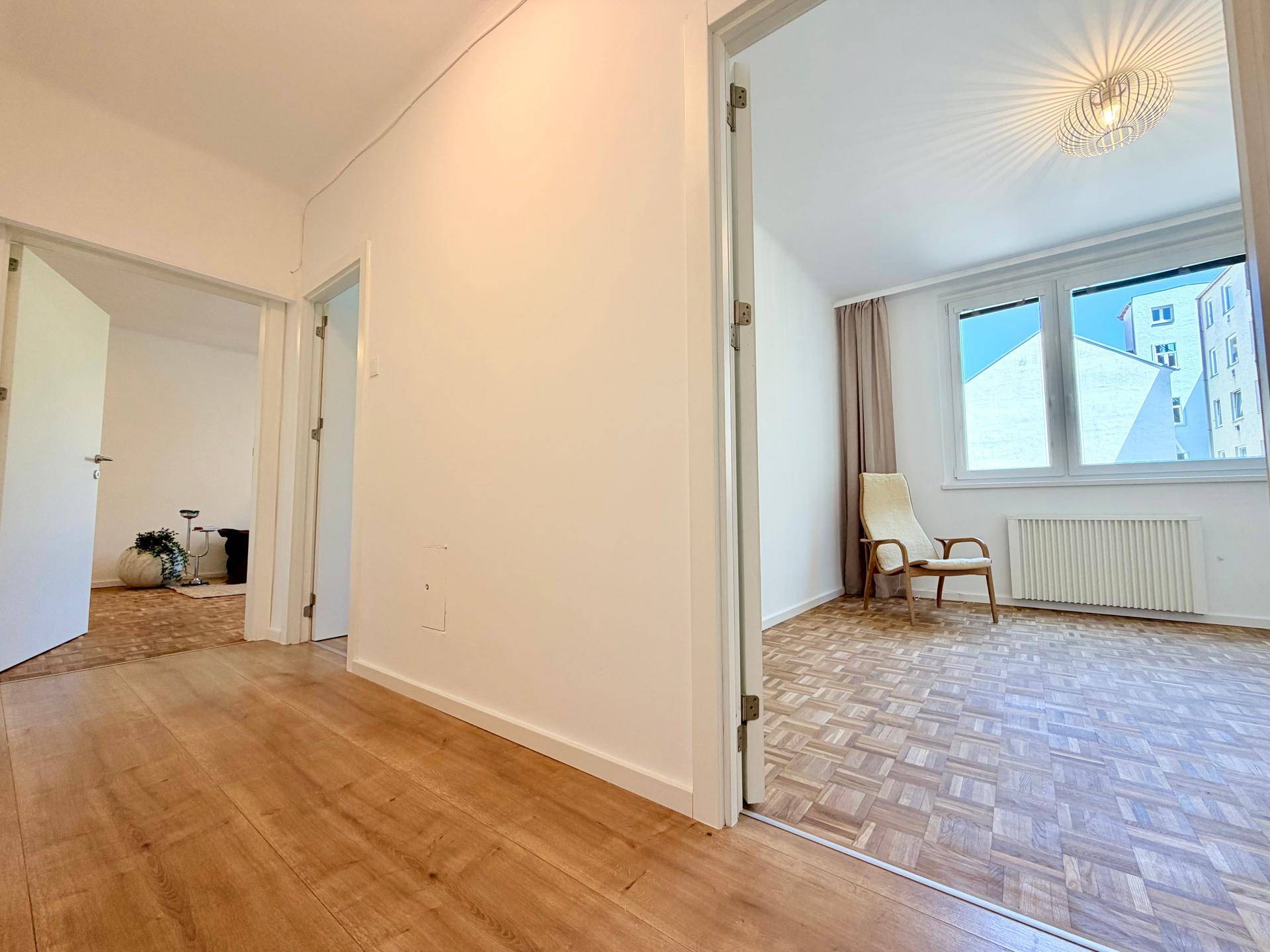 Blick vom Flur mit Laminatboden in angrenzende Zimmer mit Parkett, die viel Tageslicht erhalten.