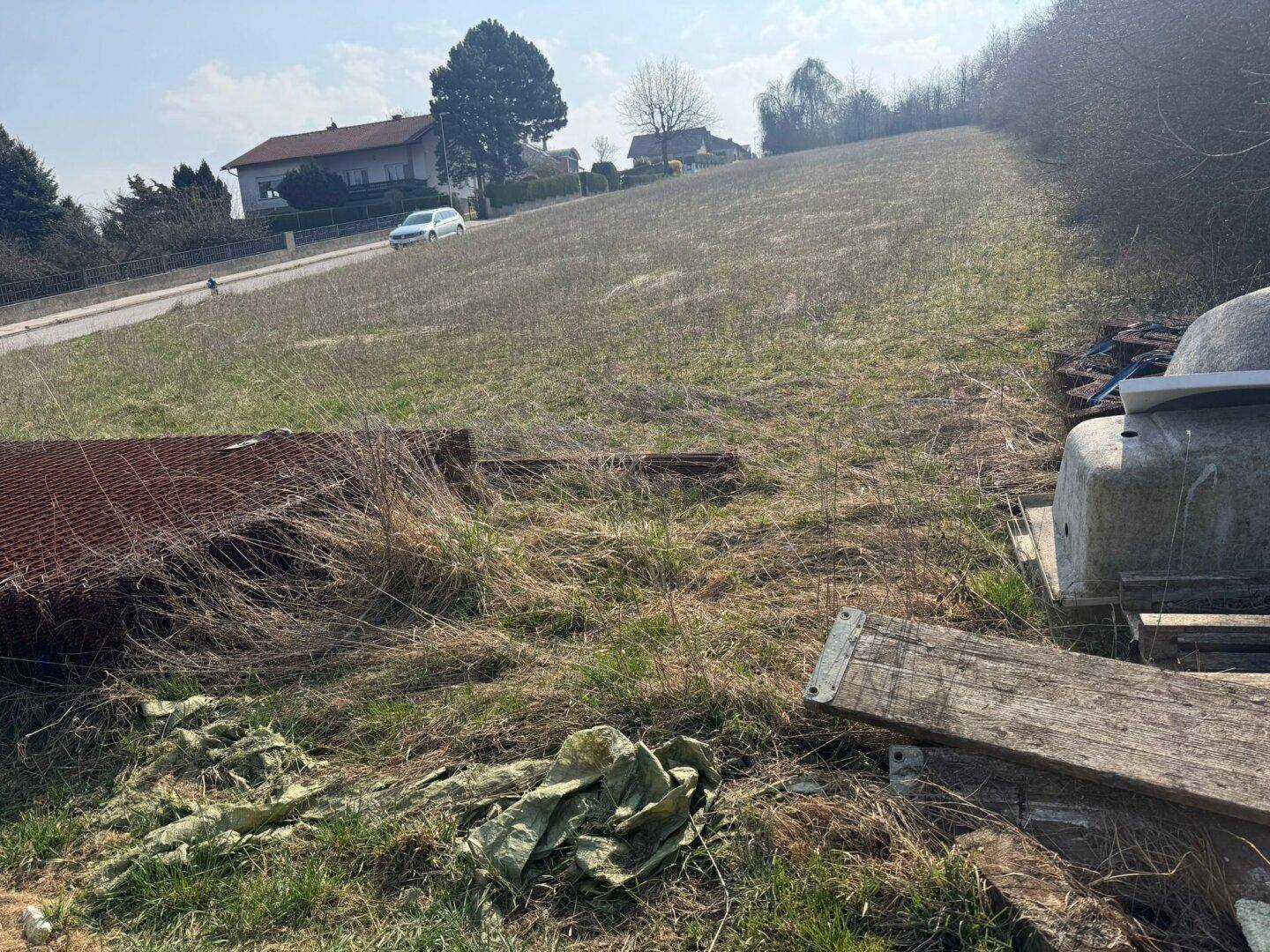 Hanglage des unbebauten Grundstücks mit Blick auf die Straße und weitere Häuser in der Ferne.