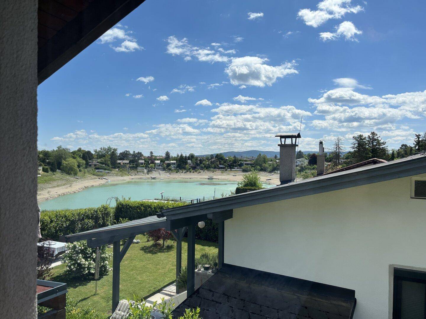 Panoramablick auf einen See und die Dächer der umliegenden Häuser unter blauem Himmel.