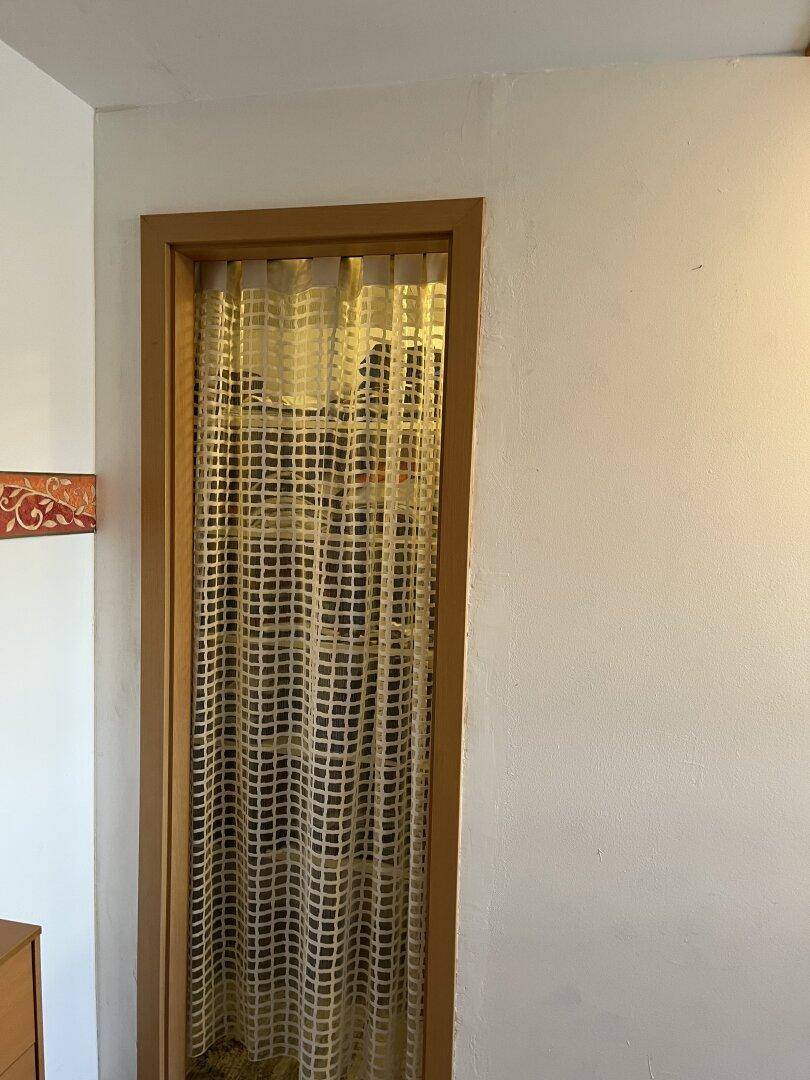 Eine Holztür mit einem dekorativen Vorhang in einem hellen Innenraum.