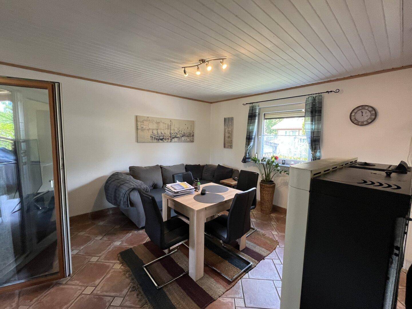 Gemütlicher Wohn-Essbereich mit Sofa, Esstisch und Zugang zur Terrasse.