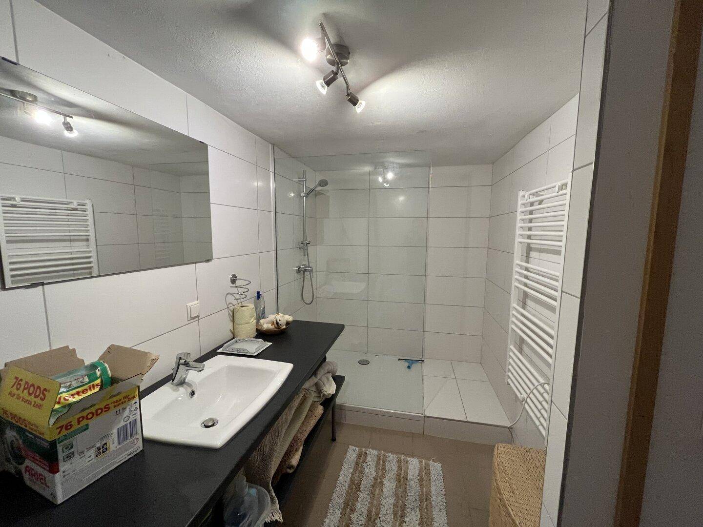 Modernes Badezimmer mit ebenerdiger Dusche, Einzelwaschbecken und Handtuchheizkörper.