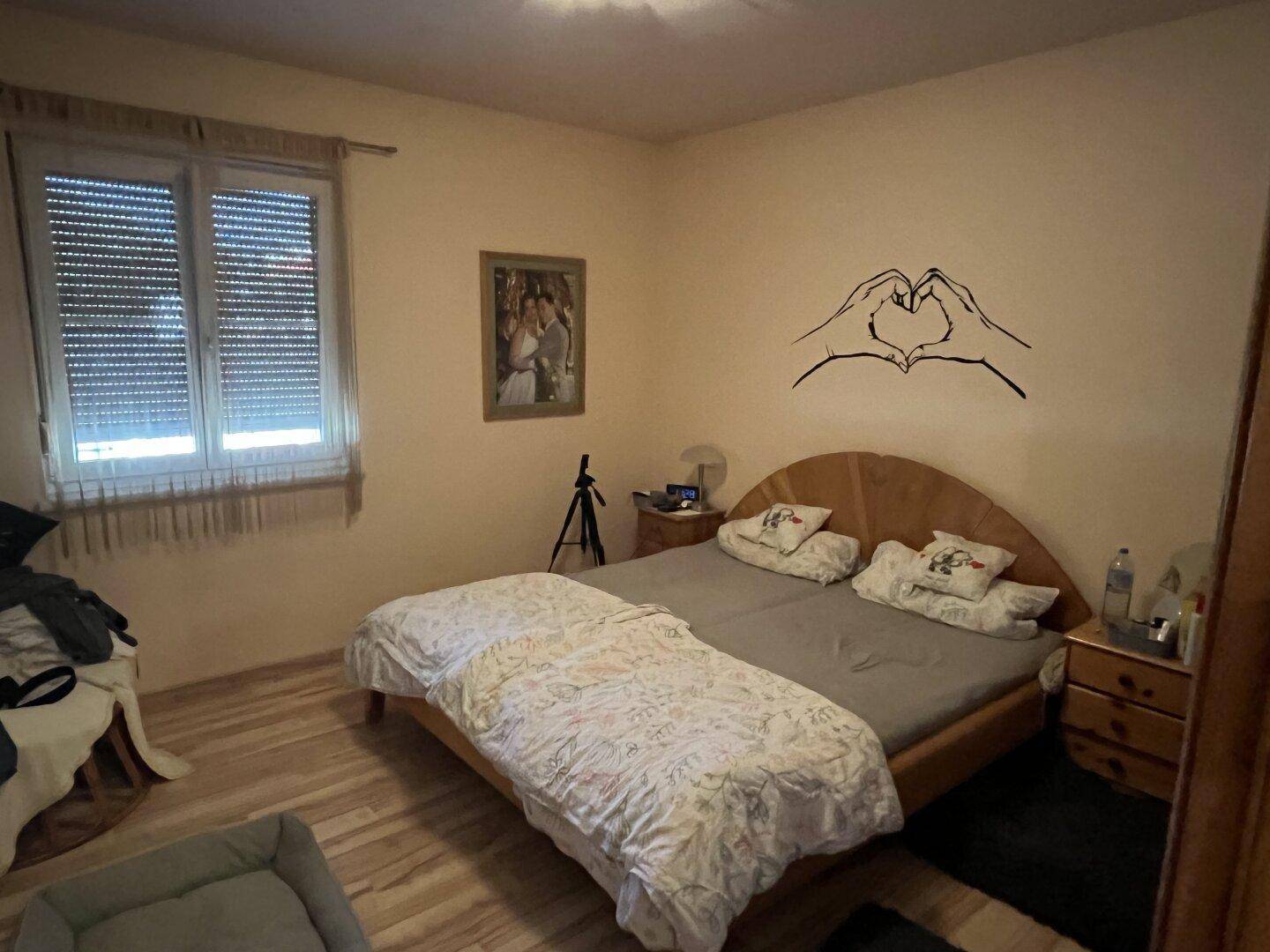 Gemütliches Schlafzimmer mit Doppelbett, Holzmöbeln und hellem Laminatboden.