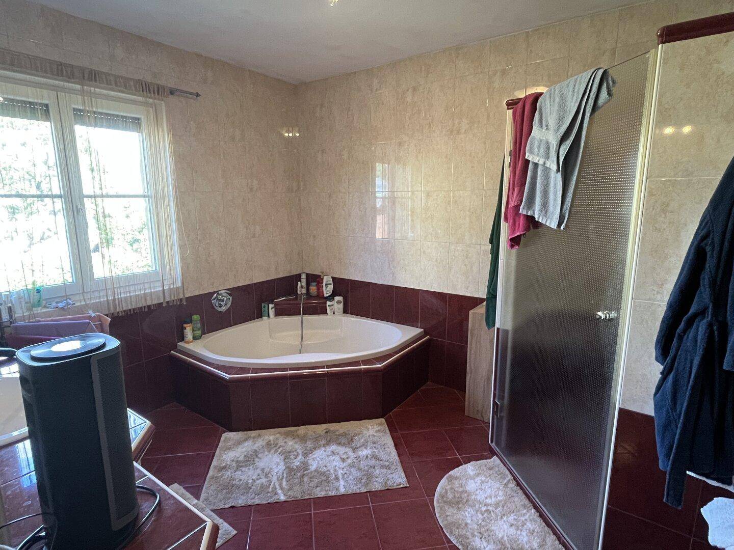 Geräumiges Badezimmer mit Eckbadewanne, Duschkabine und roten Fliesen.
