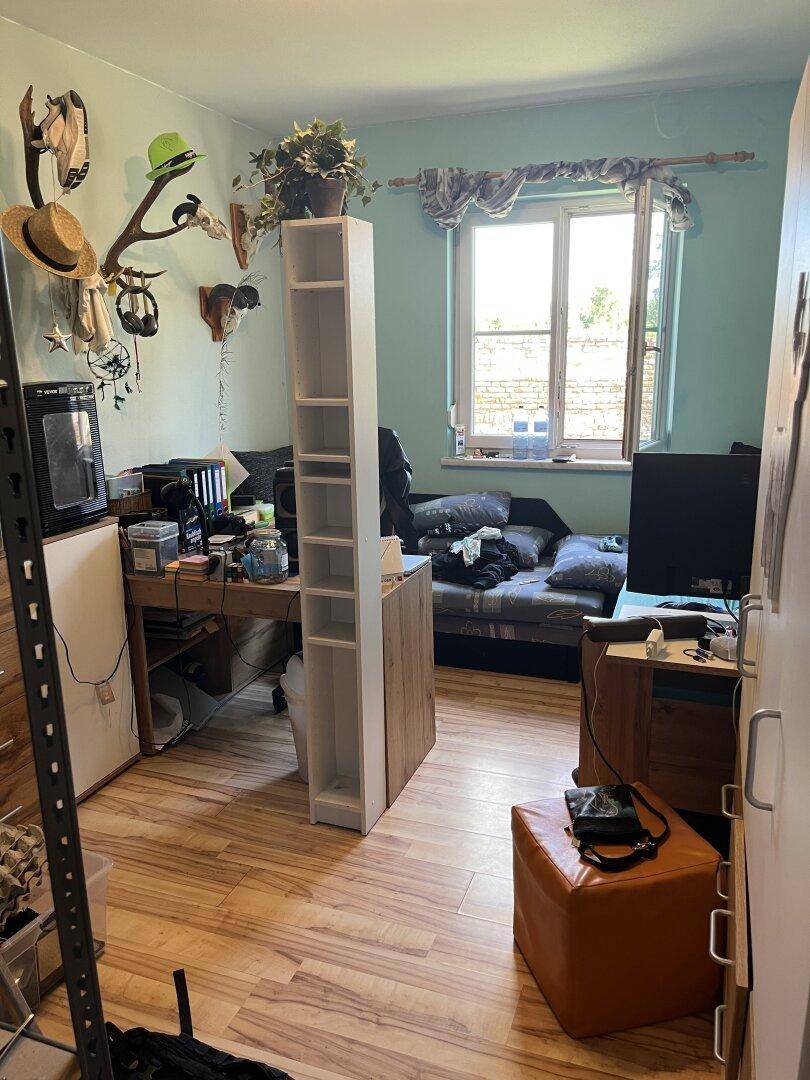 Jugendzimmer mit Schreibtisch, Bett und farbenfroher Dekoration.