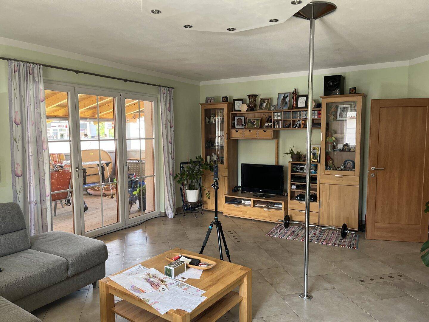 Geräumiges Wohnzimmer mit Zugang zur Terrasse, TV-Möbeln und Fliesenboden.