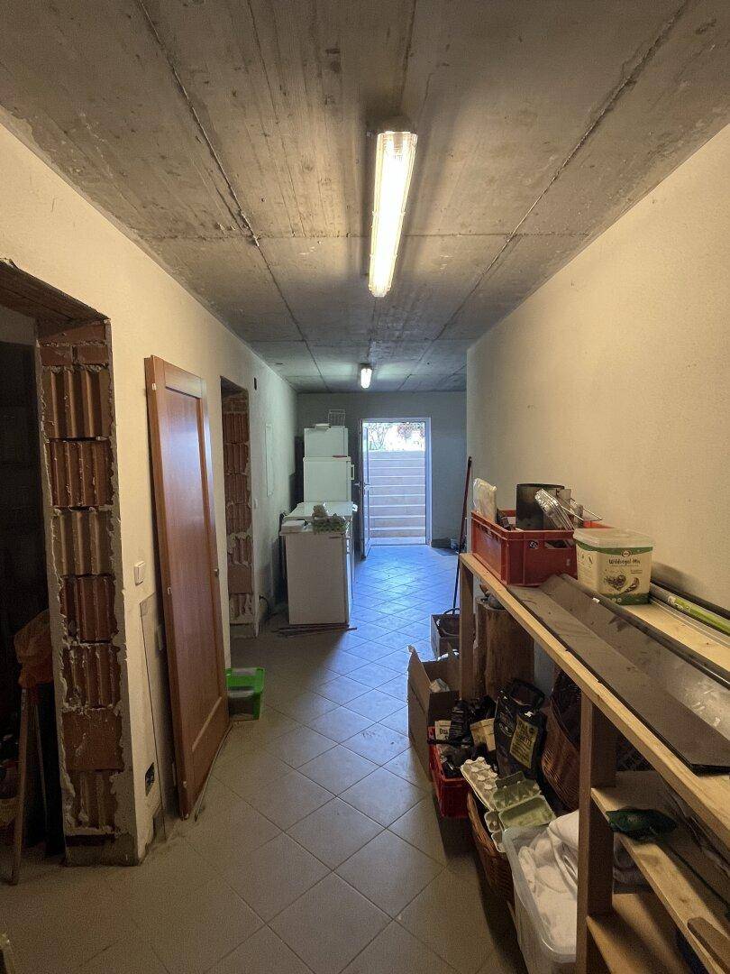 Kellerflur mit Fliesenboden, Türen zu weiteren Räumen und Treppenaufgang.