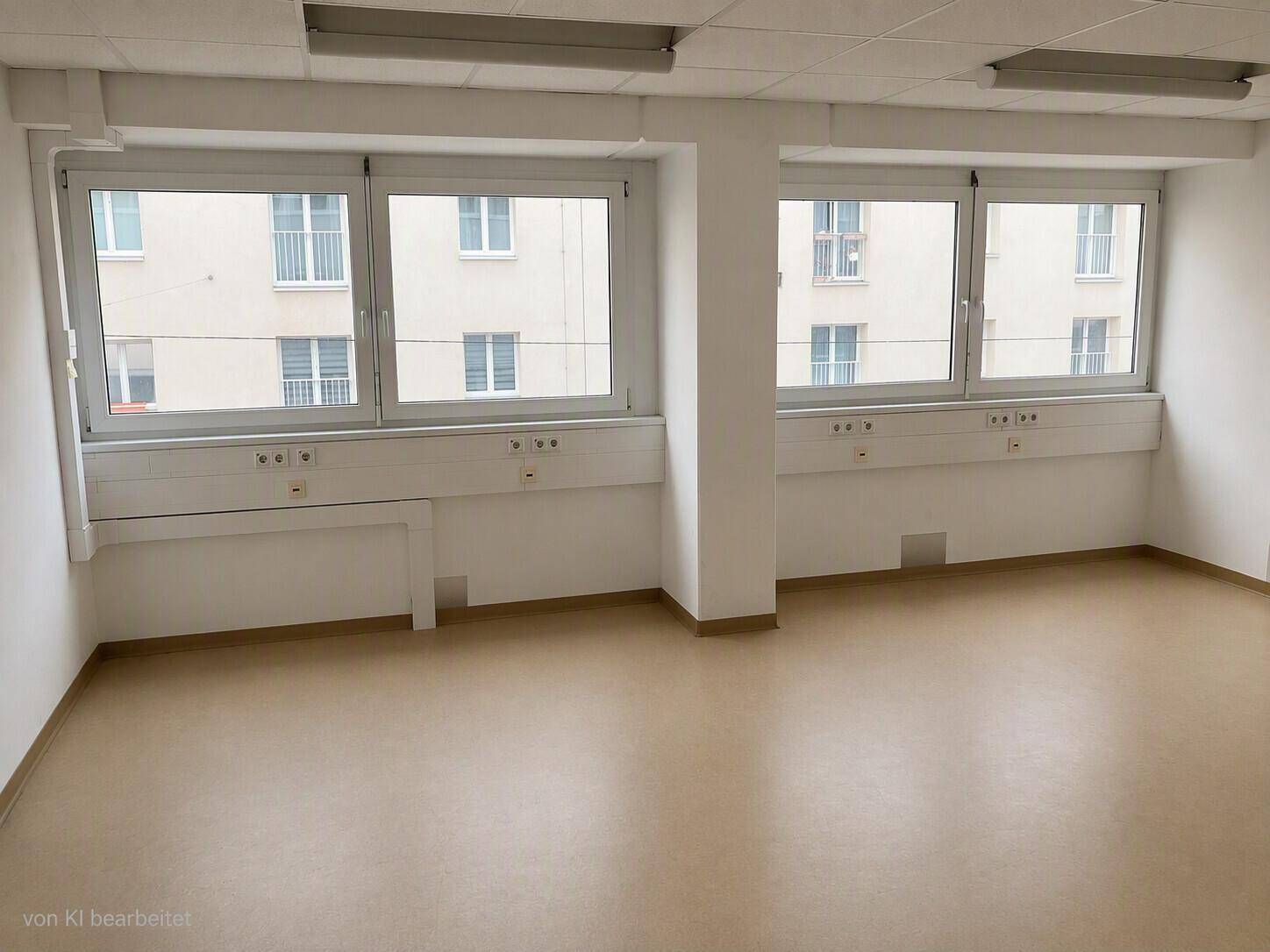 Geräumiger Büroraum mit mehreren großen Fenstern und Blick auf umliegende Gebäude, in gutem Zustand.