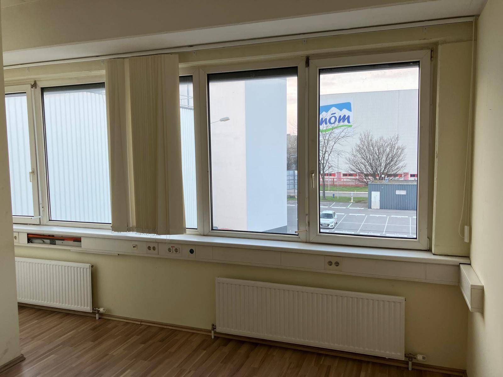 Büro mit mehreren Fenstern, die viel Tageslicht hereinlassen und einen Blick auf die Umgebung ermöglichen.