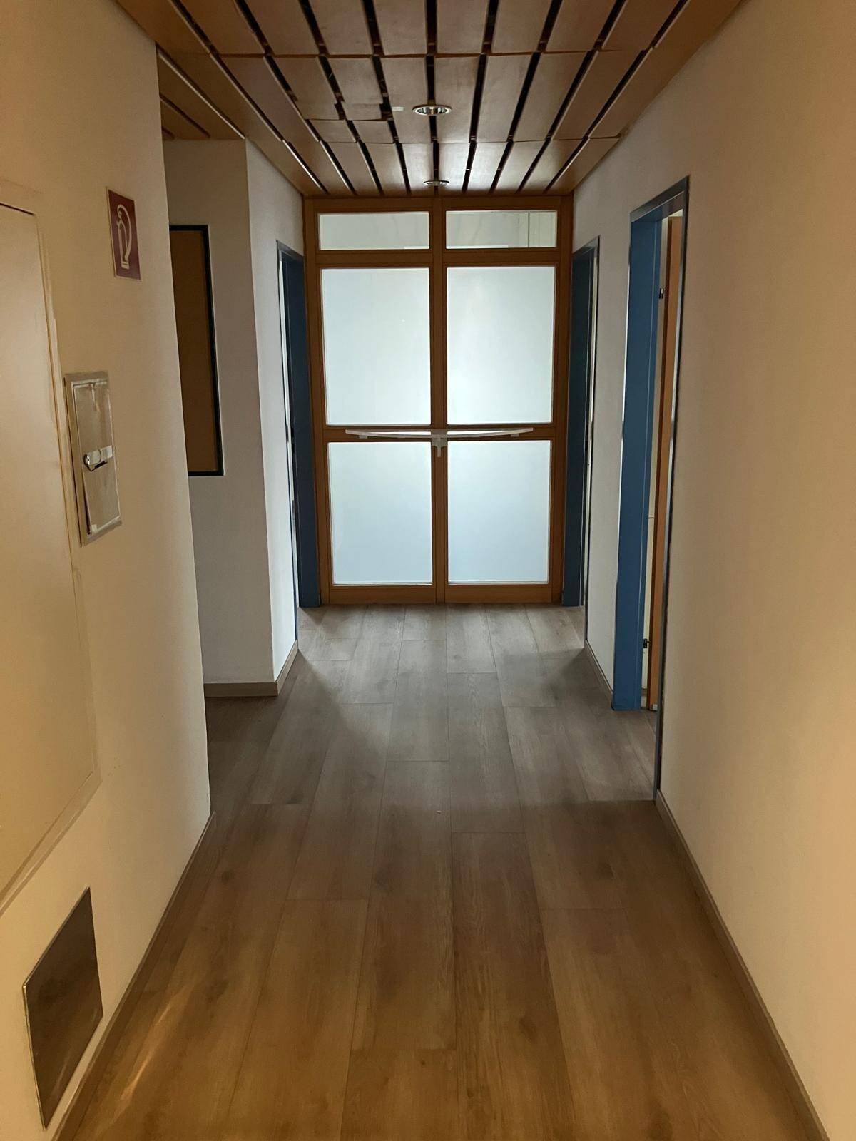 Langer Flur mit Holzdeckenverkleidung, Laminatboden und Türen zu weiteren Räumen.