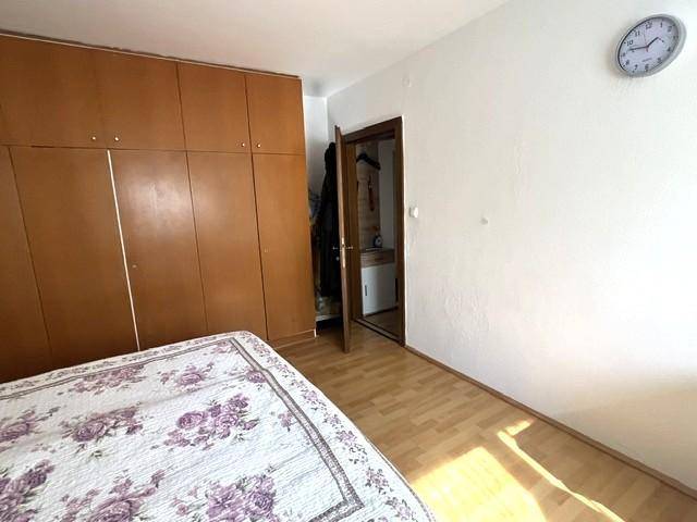 Schlafzimmer mit großem Holzschrank, Bett und hellem Laminatboden.