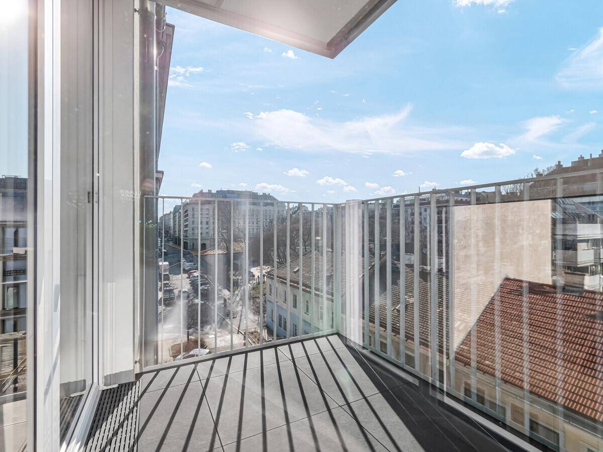 Heller Balkon mit Fliesenboden und Glasgeländer, bietet einen weiten Blick über die städtische Umgebung.