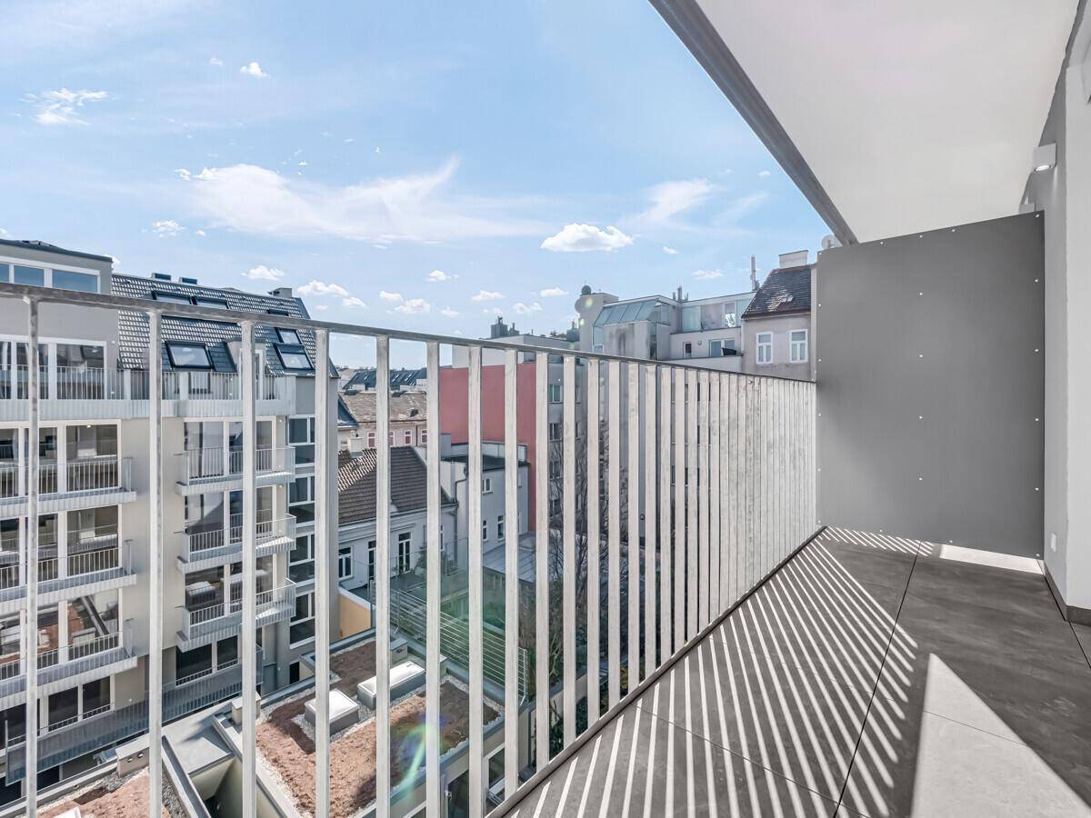 Geräumiger Balkon mit Fliesenboden und Metallgeländer, bietet einen weiten Blick über die Stadt.
