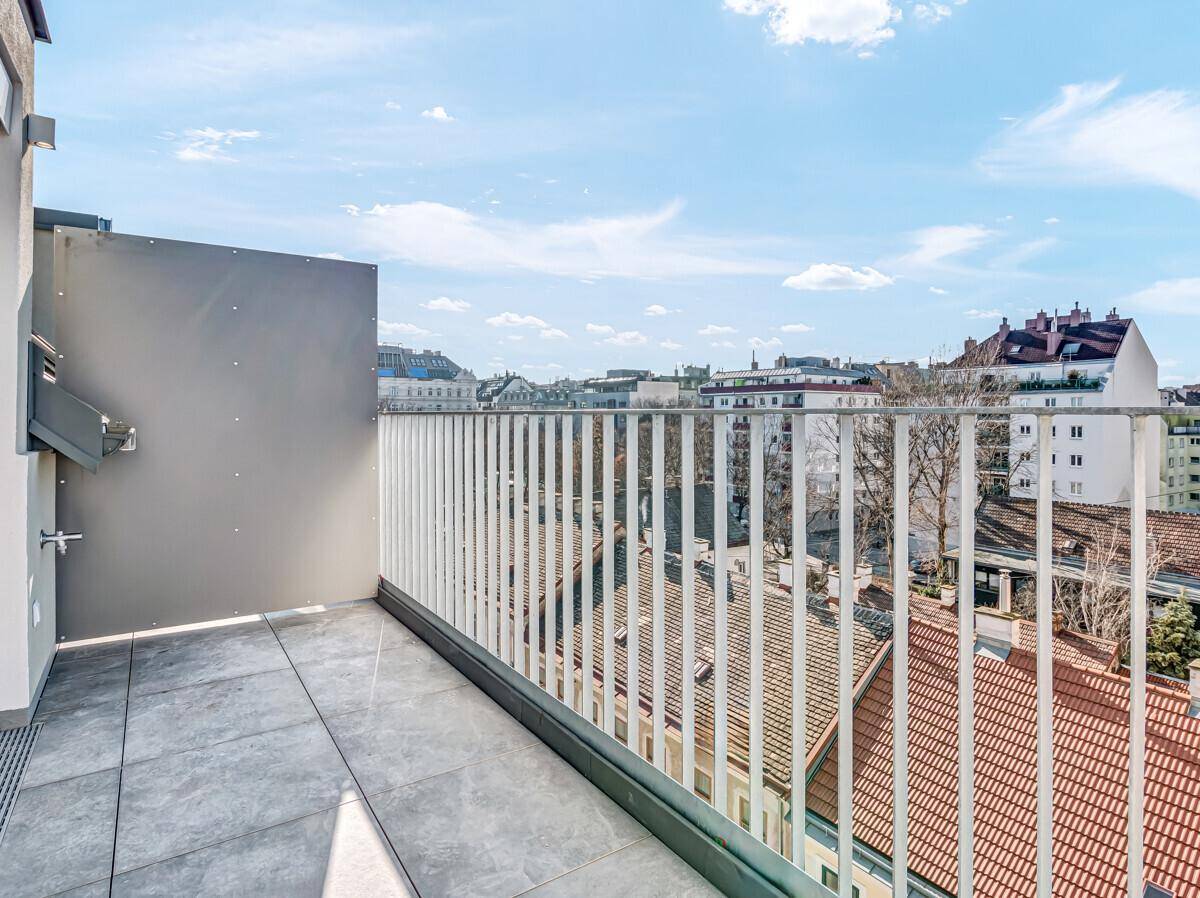 Geräumiger Balkon mit Fliesenboden und Metallgeländer, bietet einen weiten Blick über die Stadt.