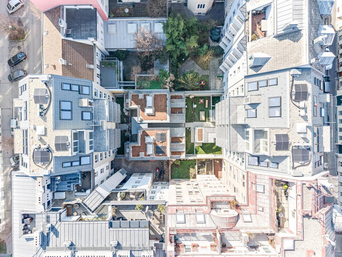 Vogelperspektive eines Wohnkomplexes mit Innenhöfen, Dachterrassen und Grünflächen in der Stadt.