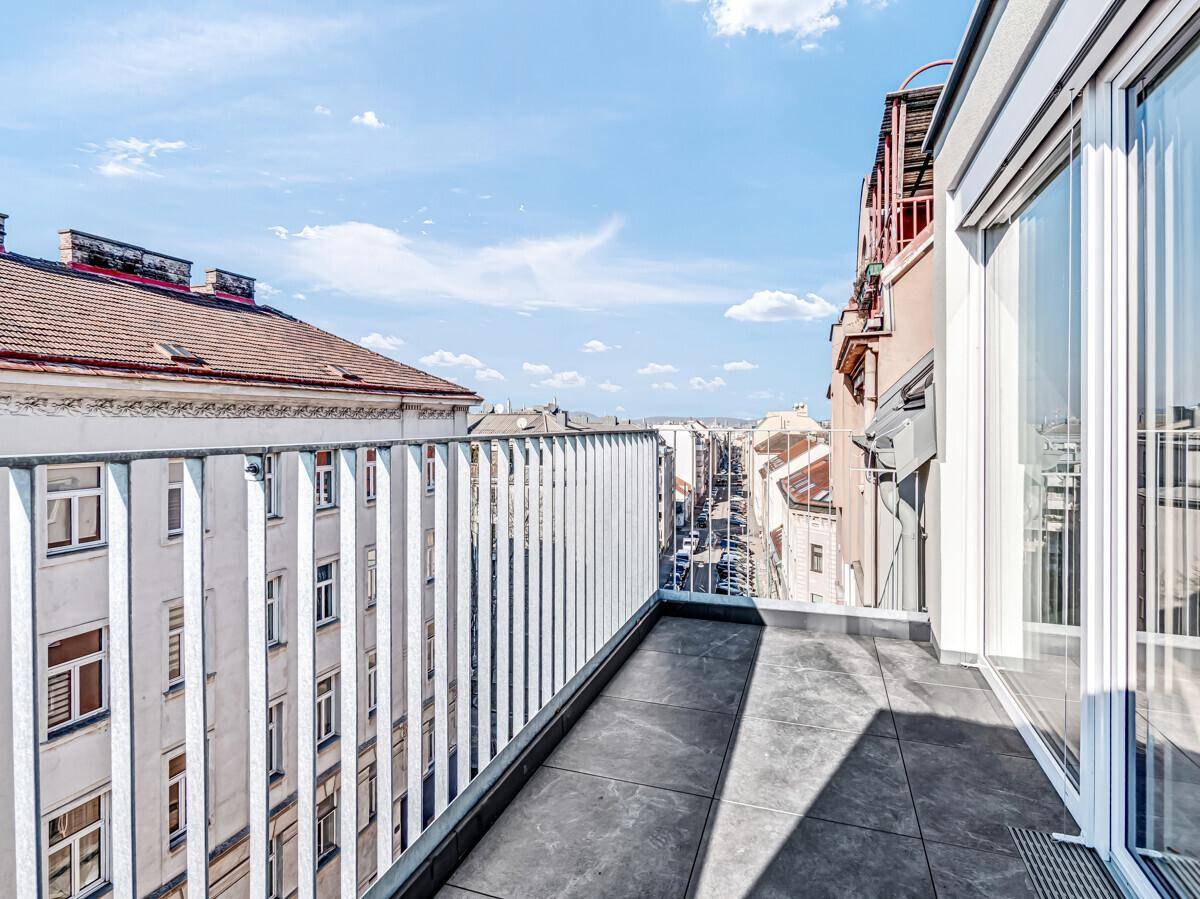 Geräumiger Balkon mit Fliesenboden und Metallgeländer, bietet einen weiten Blick über die Stadt.
