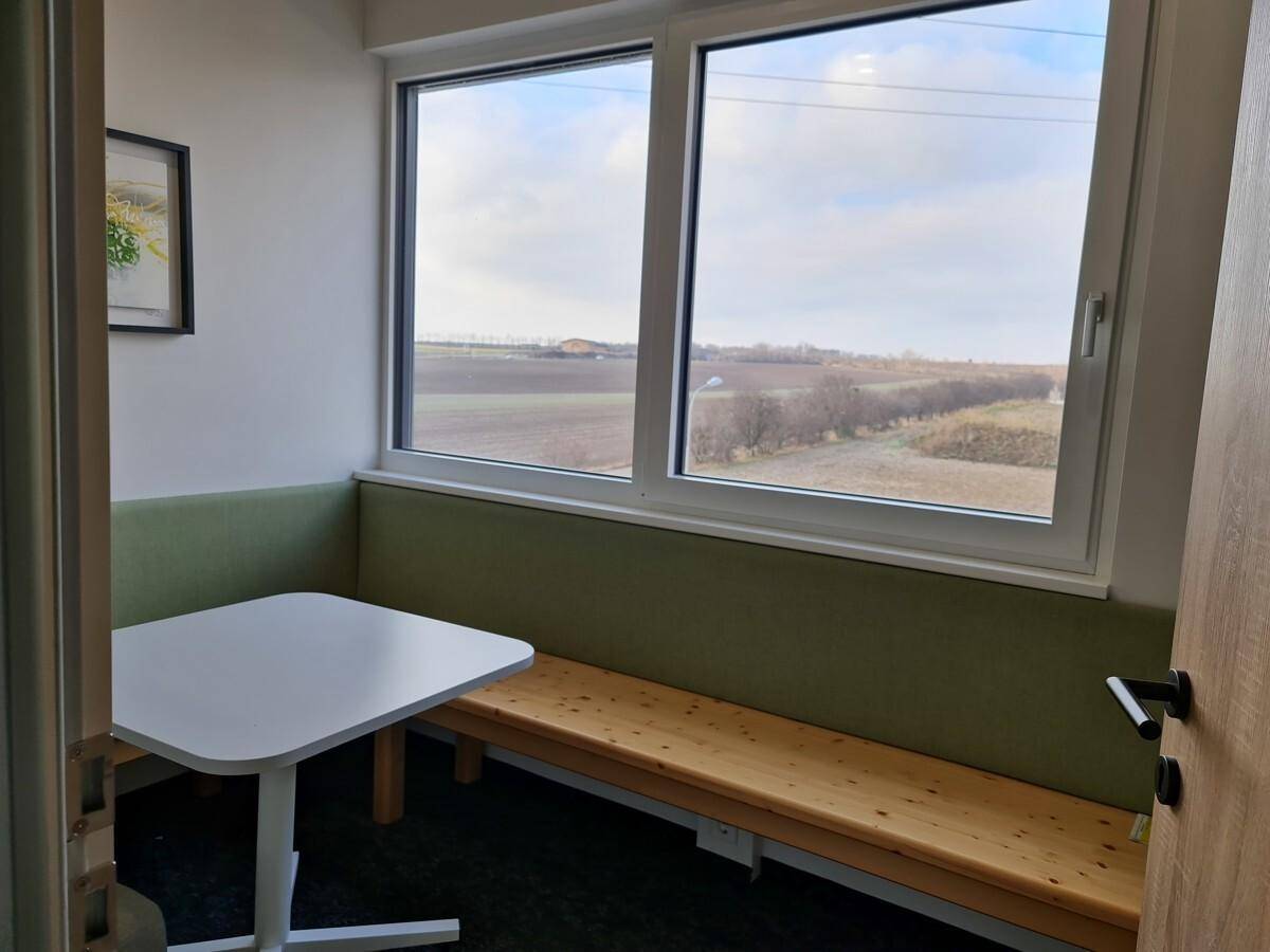 Gemütliche Sitzecke mit Bank, Tisch und großem Fenster mit Blick ins Grüne.