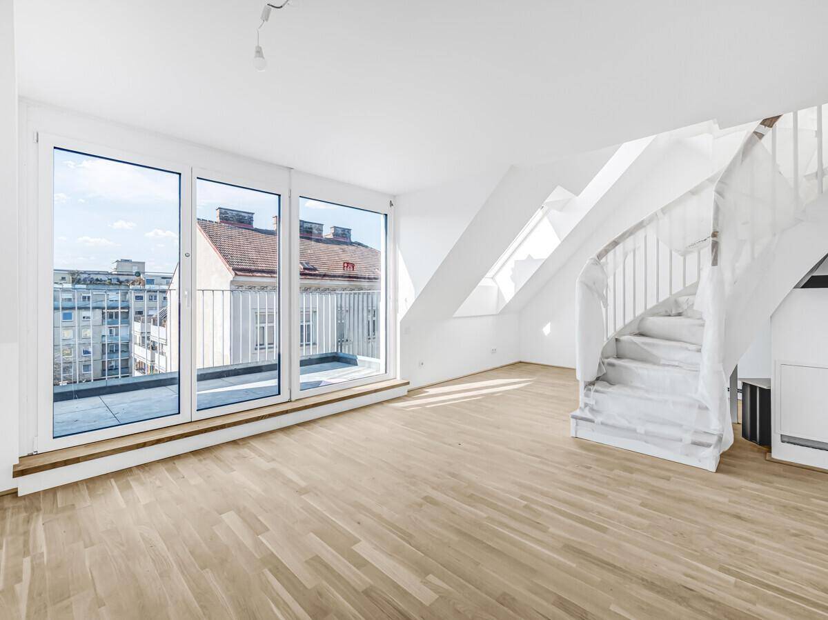 Heller Dachgeschossraum mit Holzboden, Wendeltreppe und großen Dachfenstern, bietet viel Tageslicht.