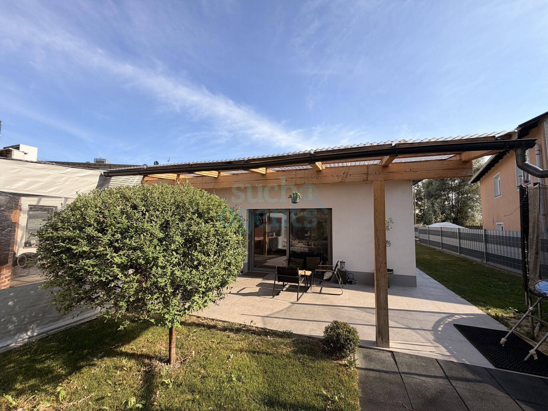 Überdachte Terrasse mit Sitzgelegenheiten, Garten und Zugang zum Haus.