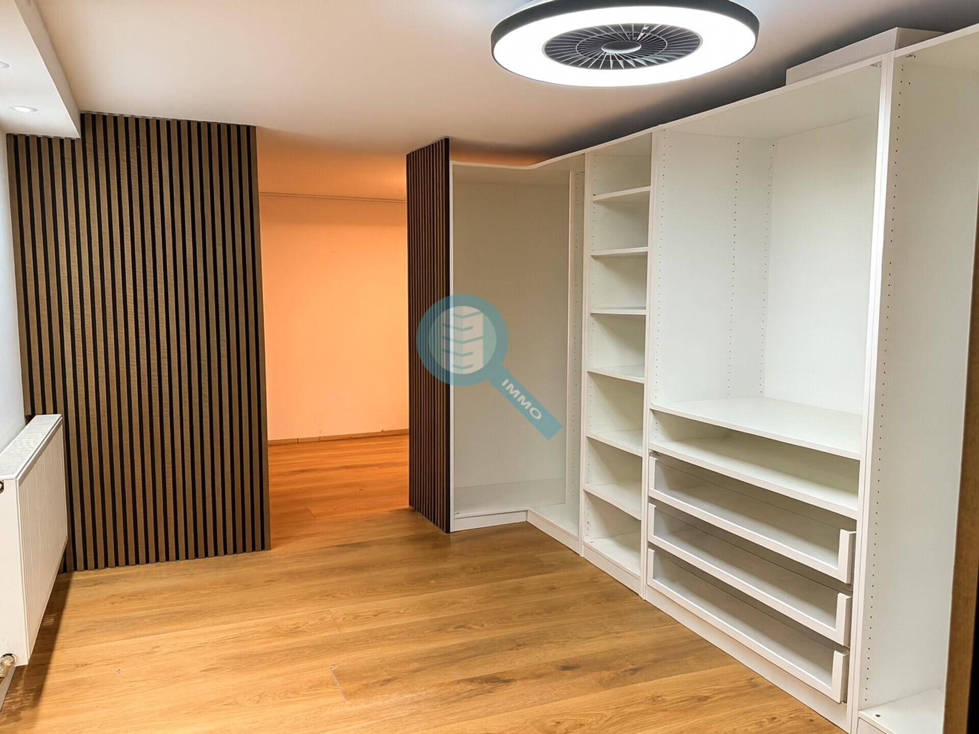 Heller Raum mit modernem Einbauschrank, Holzfußboden und dekorativer Lamellenwand.