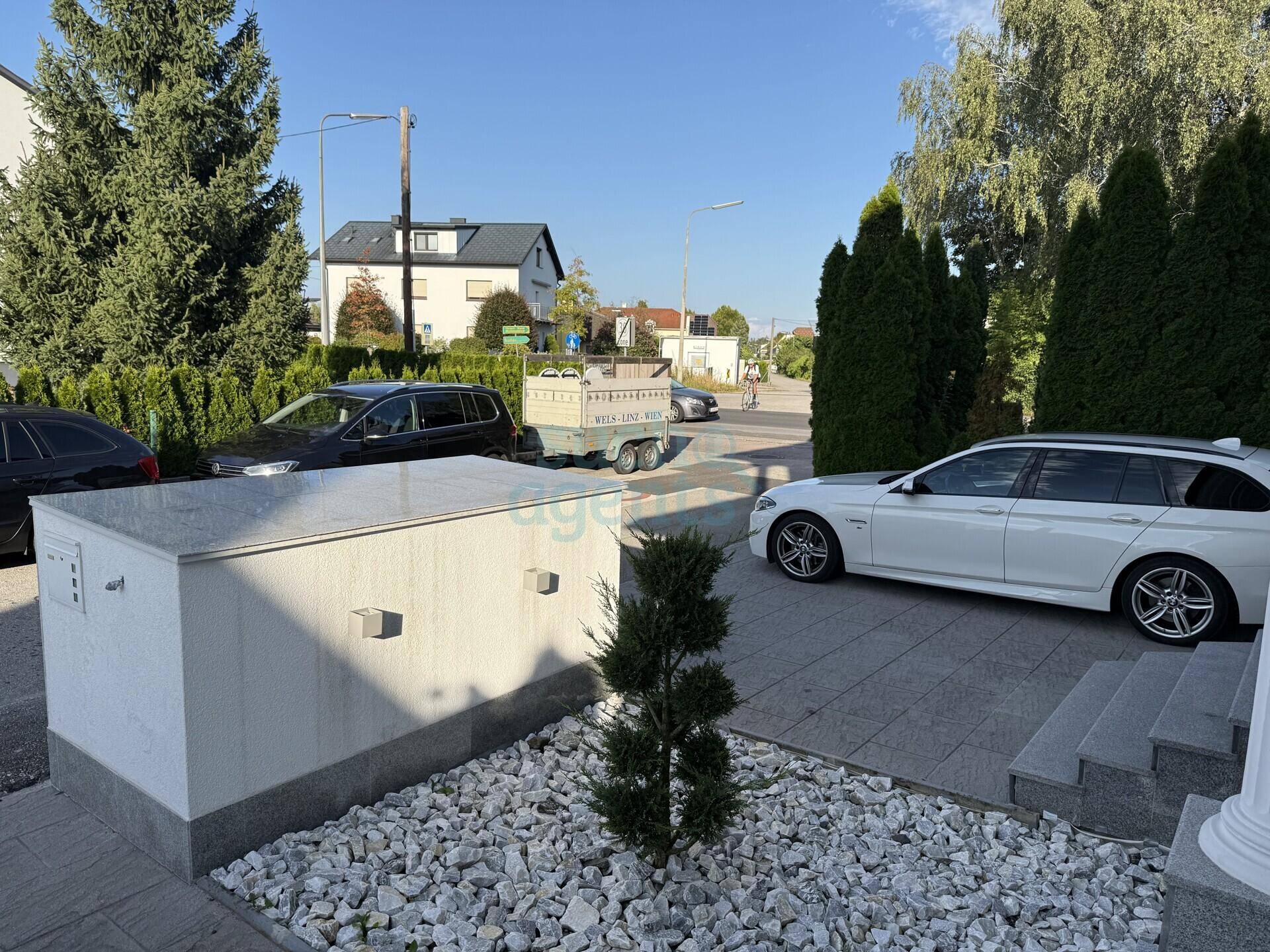 Blick auf die ruhige Wohnstraße mit gepflegtem Vorgarten und Bäumen.