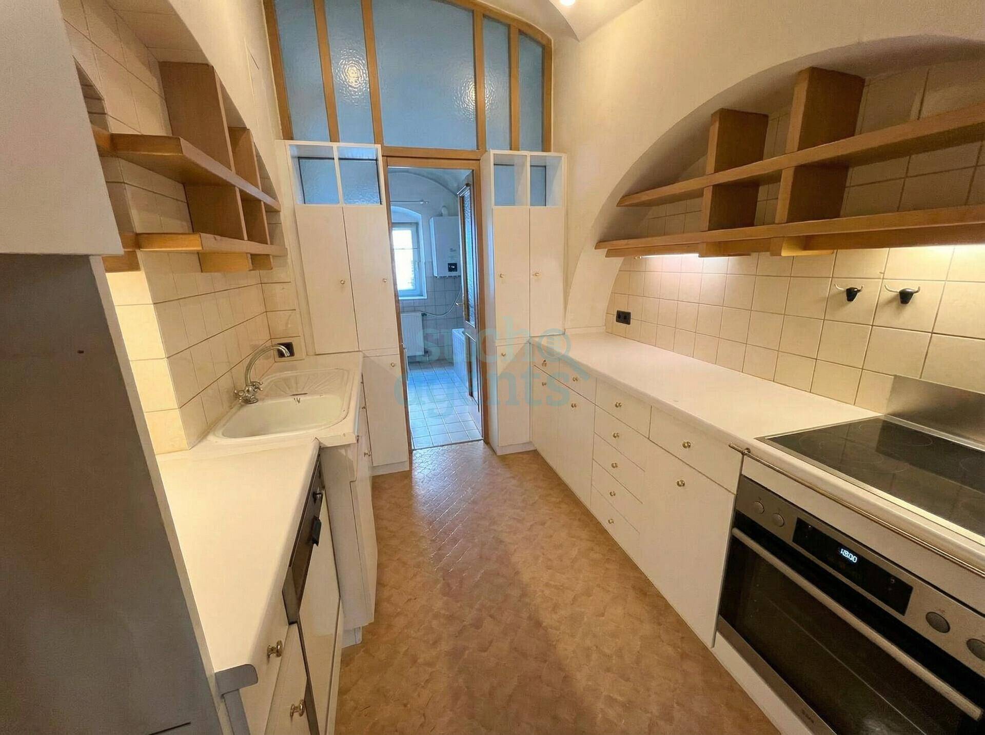 Kleine Küche mit weißen Einbauschränken, Fliesenrückwand und gewölbter Decke.