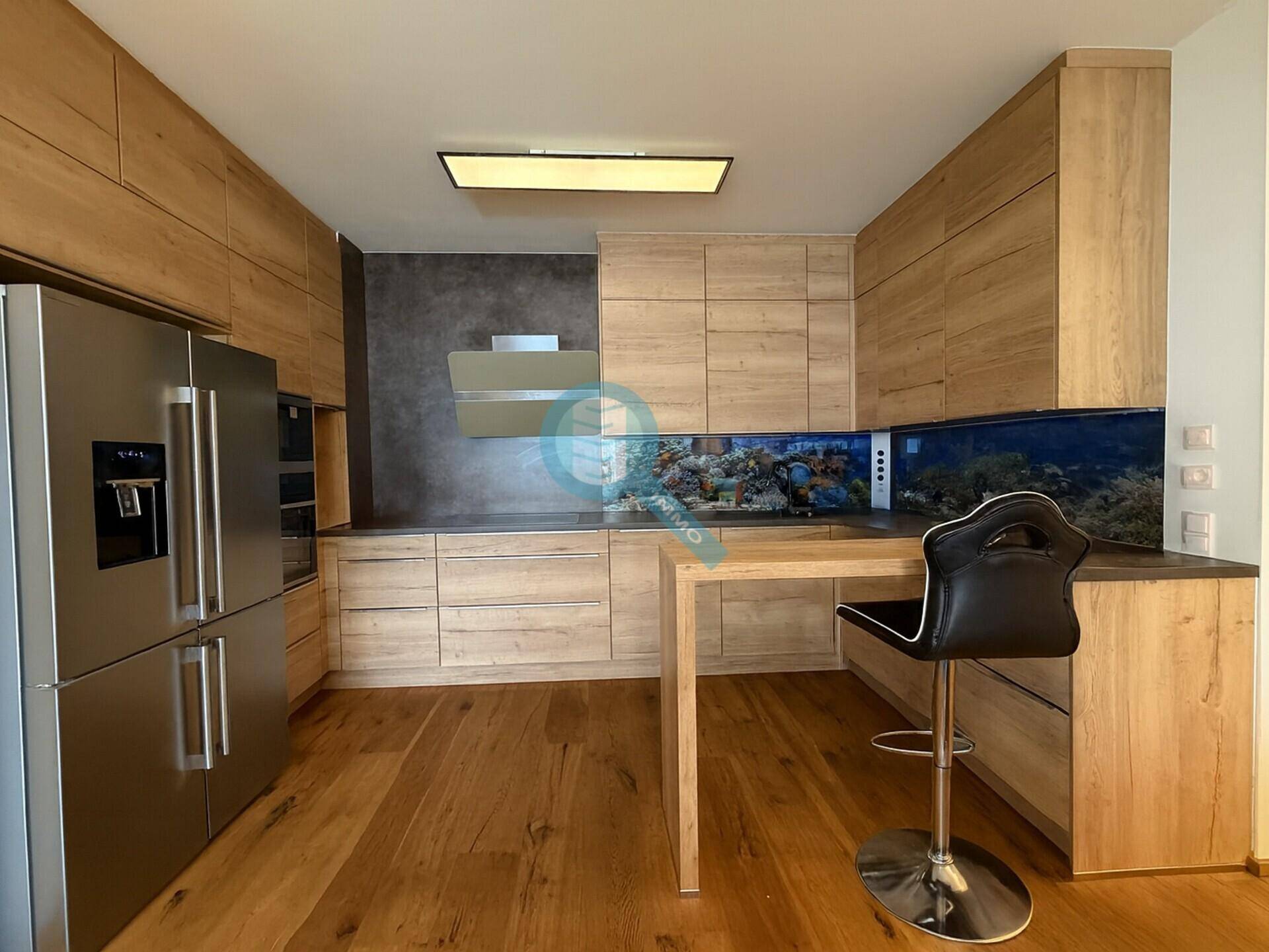 Moderne Einbauküche mit Holzfronten, Edelstahlgeräten und einer integrierten Frühstücksbar.