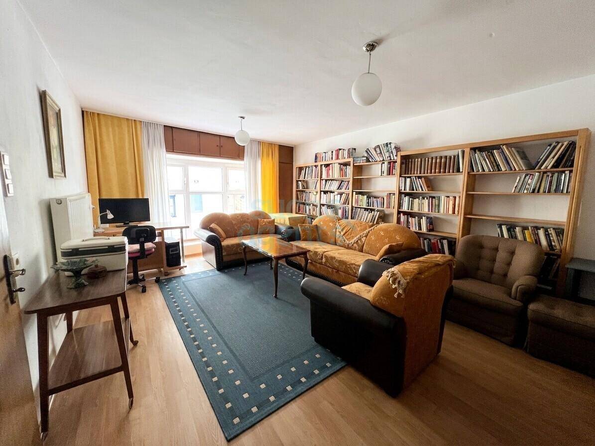 Gemütliches Wohnzimmer mit umfangreicher Büchersammlung, bequemen Sofas und einem Arbeitsbereich am Fenster.