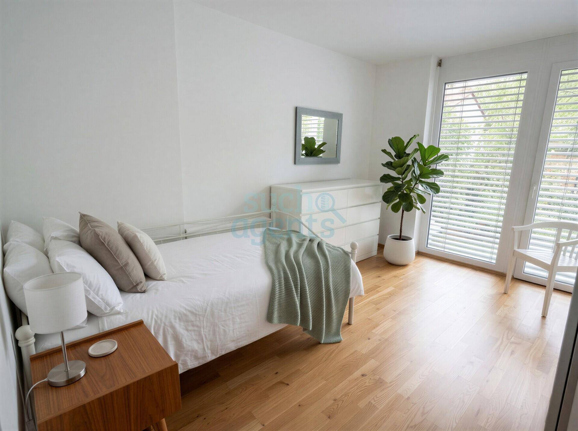 Gemütliches Schlafzimmer mit Einzelbett, Nachttisch und großem Fenster für viel Helligkeit.