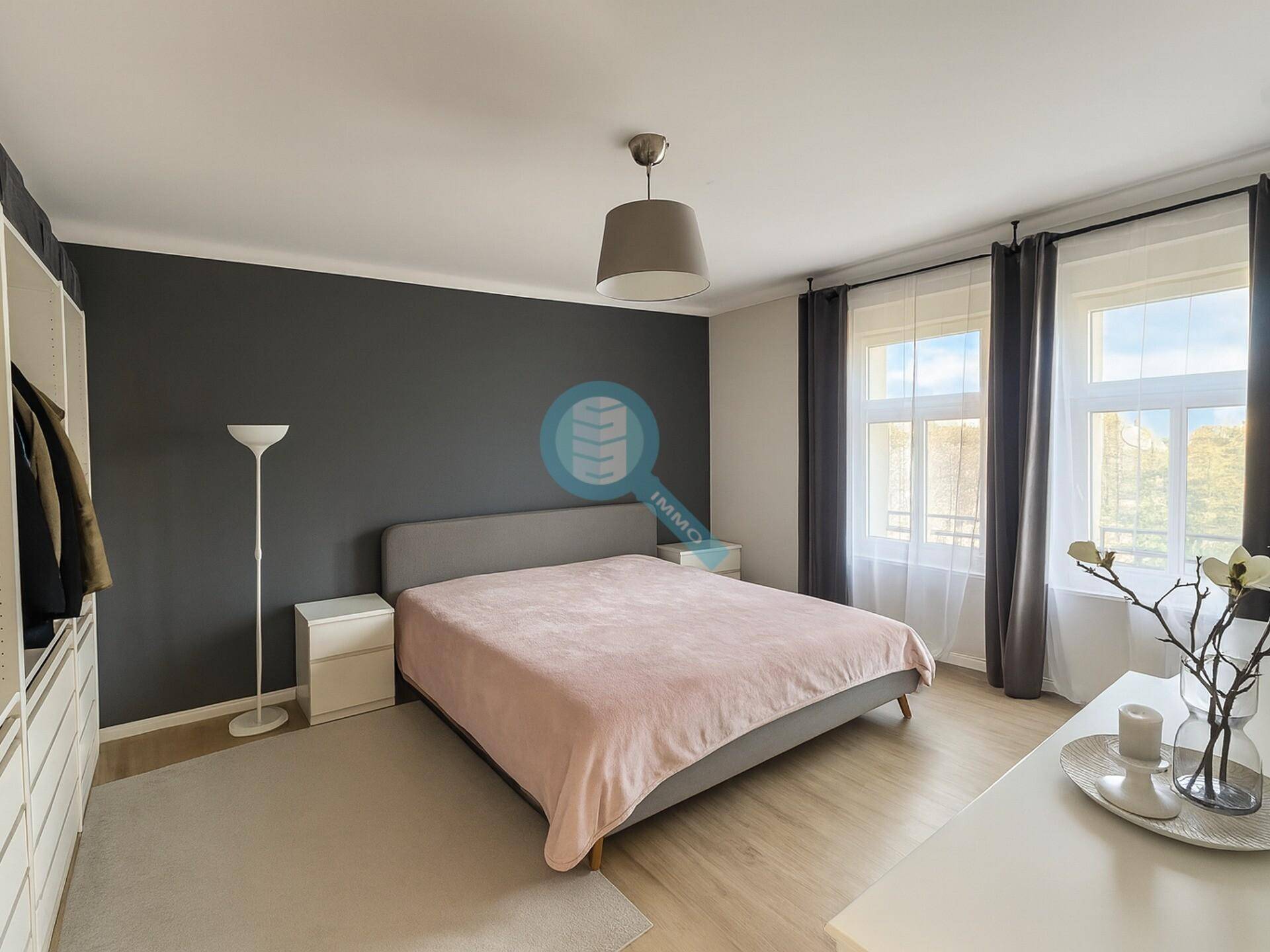 Helles Schlafzimmer mit Doppelbett, dunkler Akzentwand und großem Kleiderschrank.