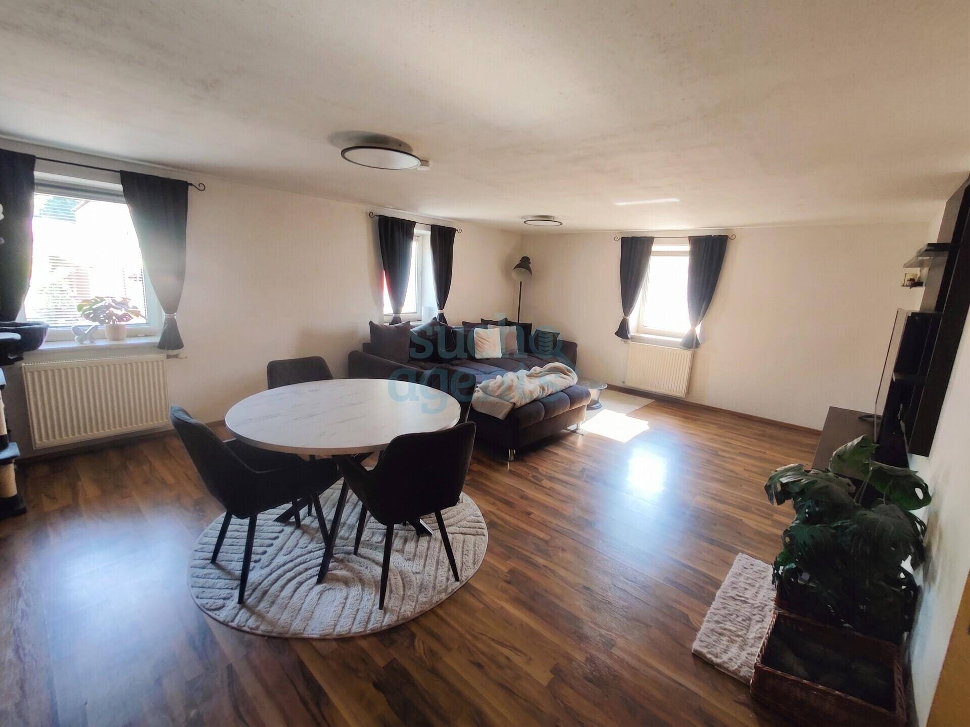 Heller Wohn- und Essbereich mit Holzboden, Esstisch und gemütlichem Sofa.