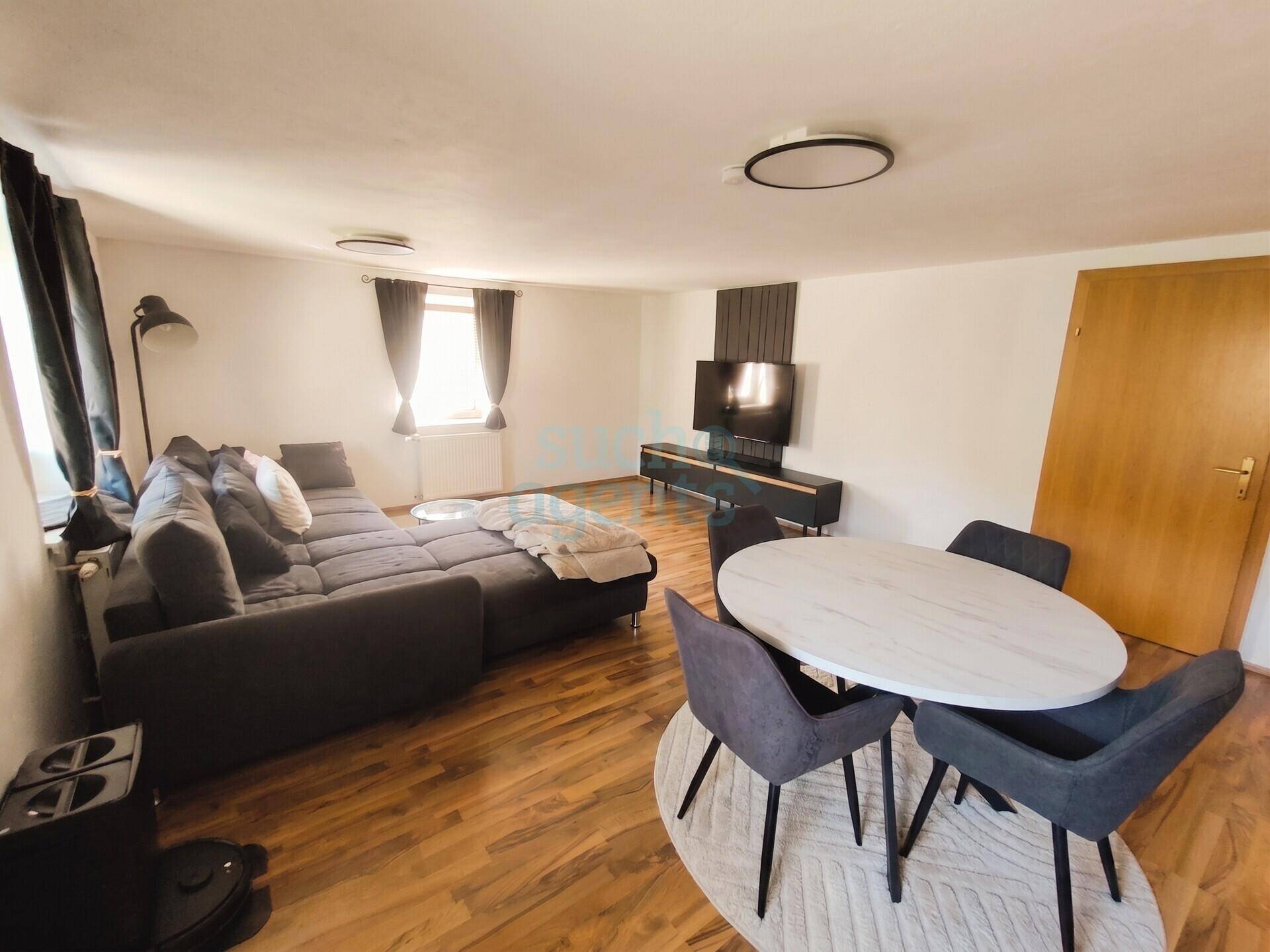 Geräumiger Wohnbereich mit Esstisch, großem Sofa und Fernseher.