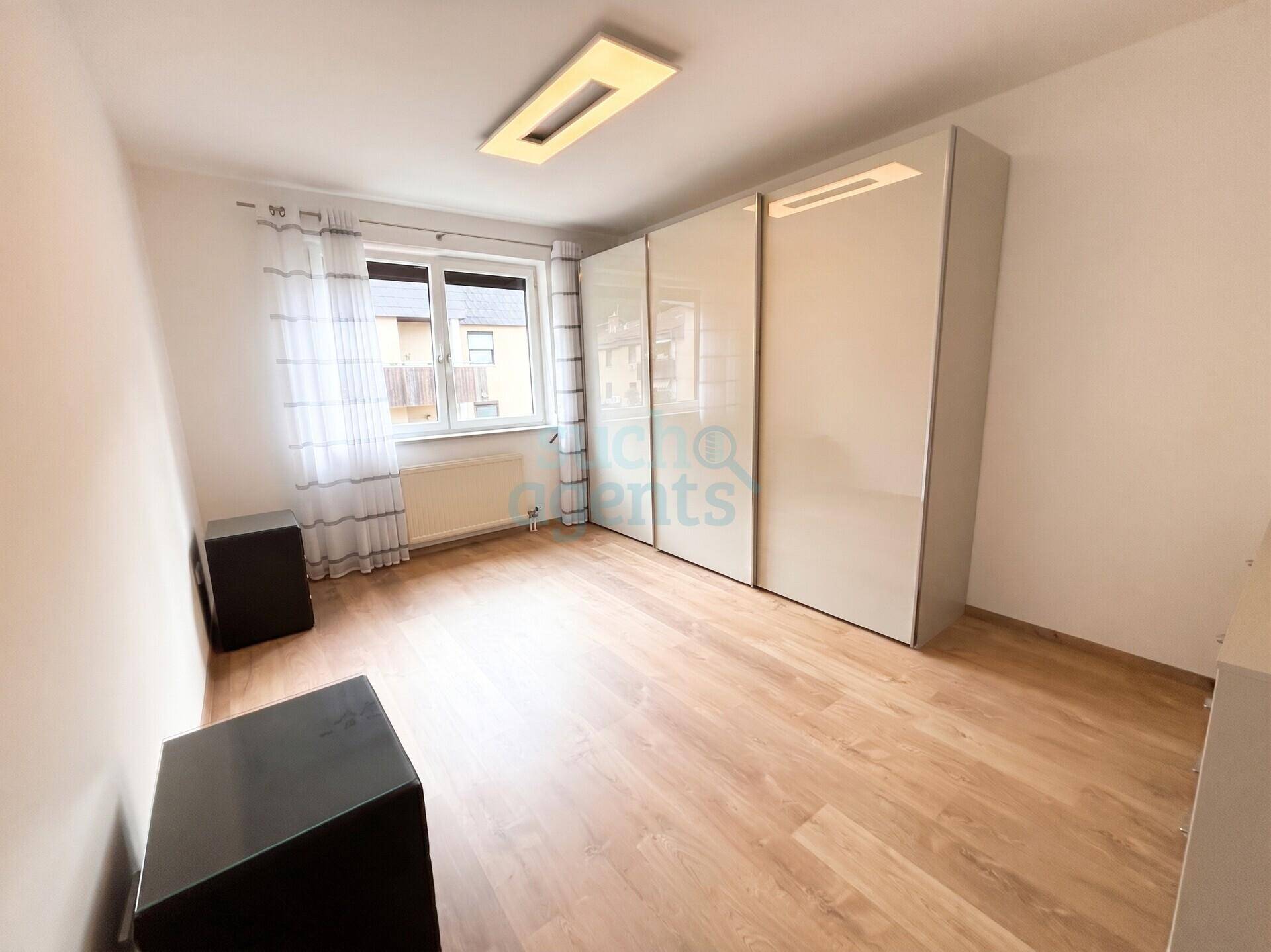 Schlafzimmer mit Laminatboden, großem Fenster und modernem Einbauschrank.