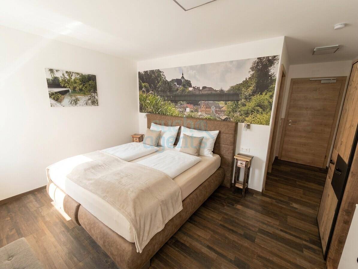 Helles Schlafzimmer mit großem Doppelbett, Holzboden und einer beeindruckenden Wandtapete mit Landschaftsmotiv.