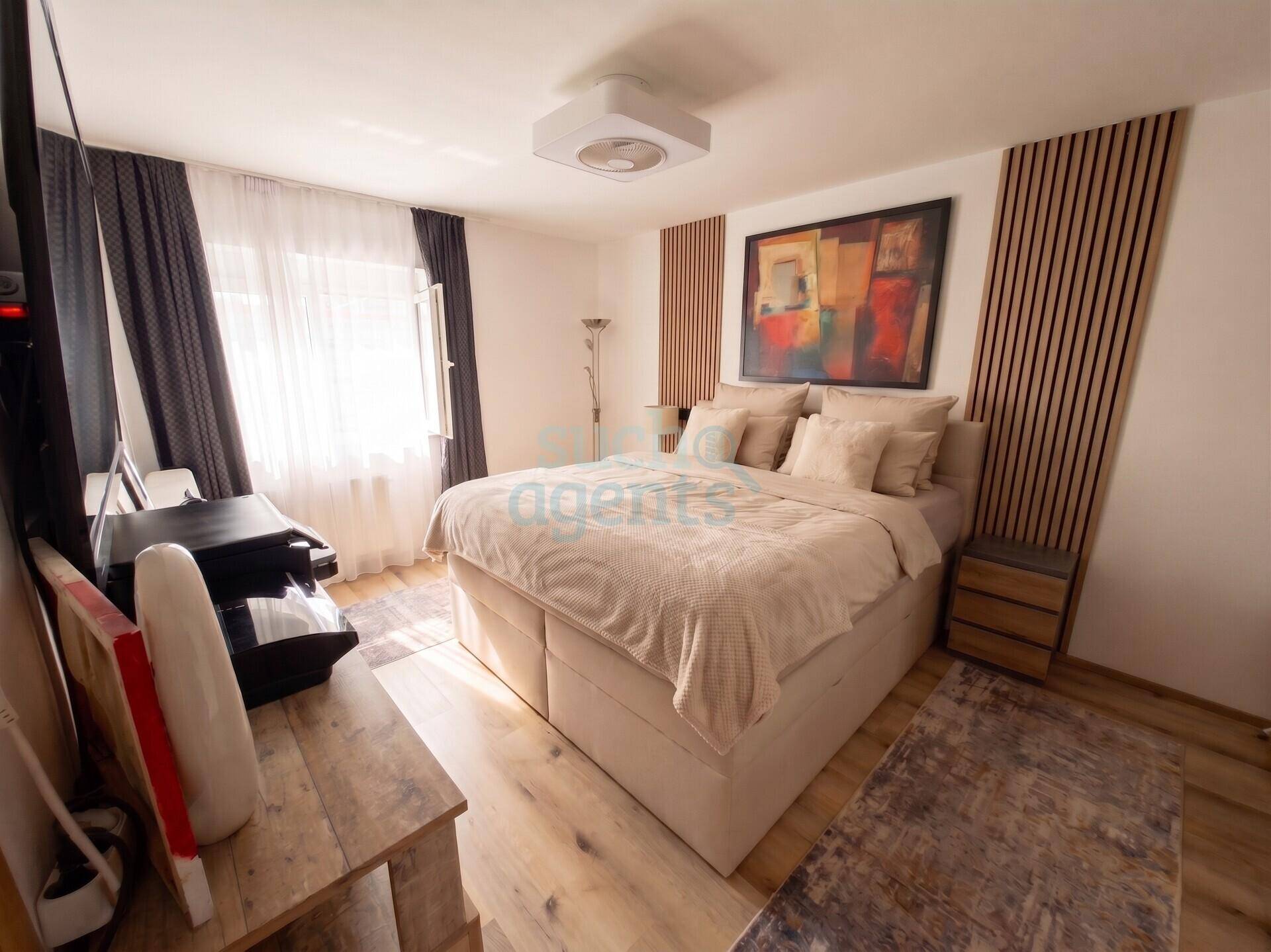 Gemütliches Schlafzimmer mit großem Bett, Holzakzenten an der Wand und viel natürlichem Licht durch das Fenster.