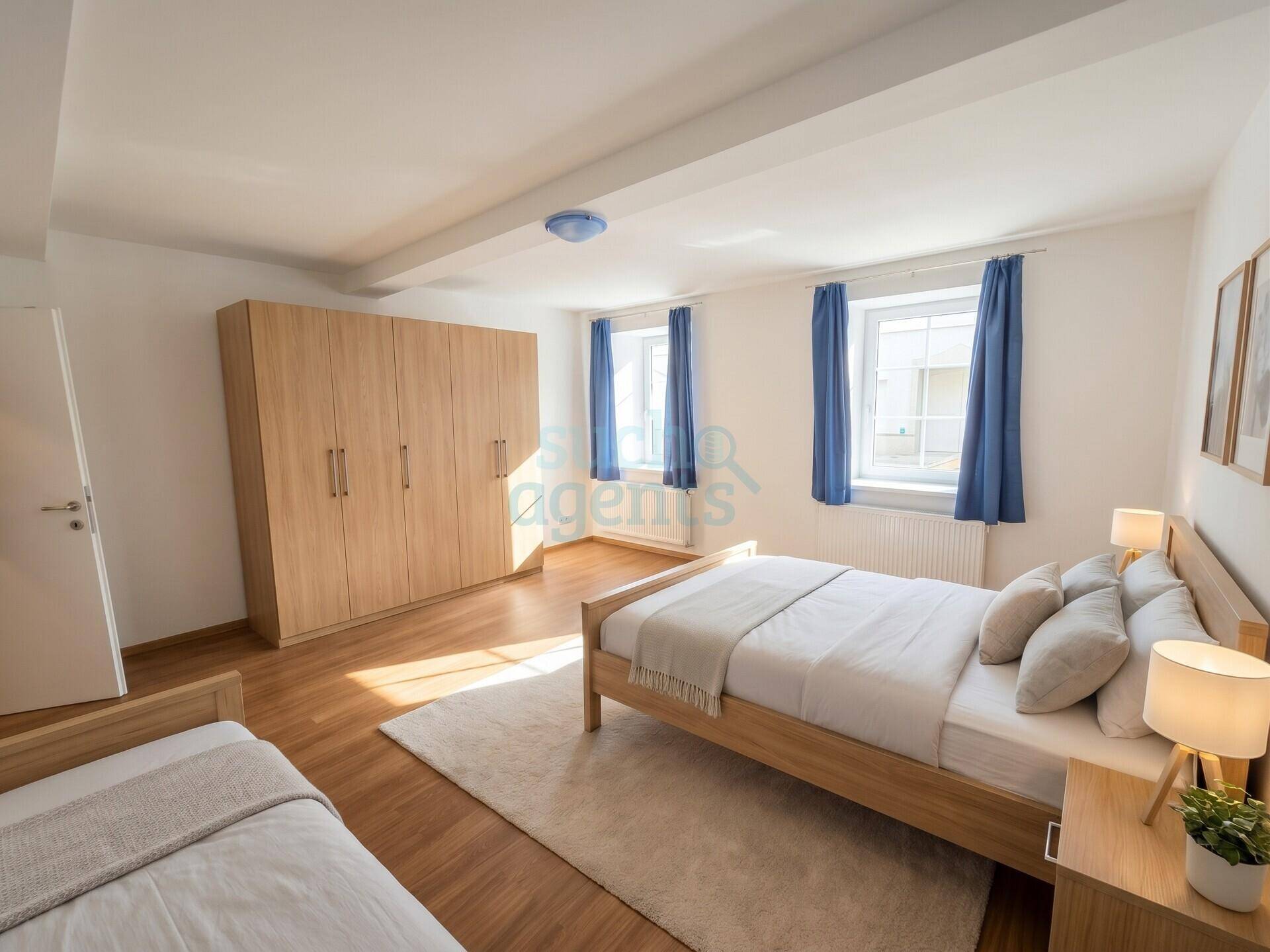 Helles Schlafzimmer mit zwei Betten, großem Kleiderschrank und Holzboden.