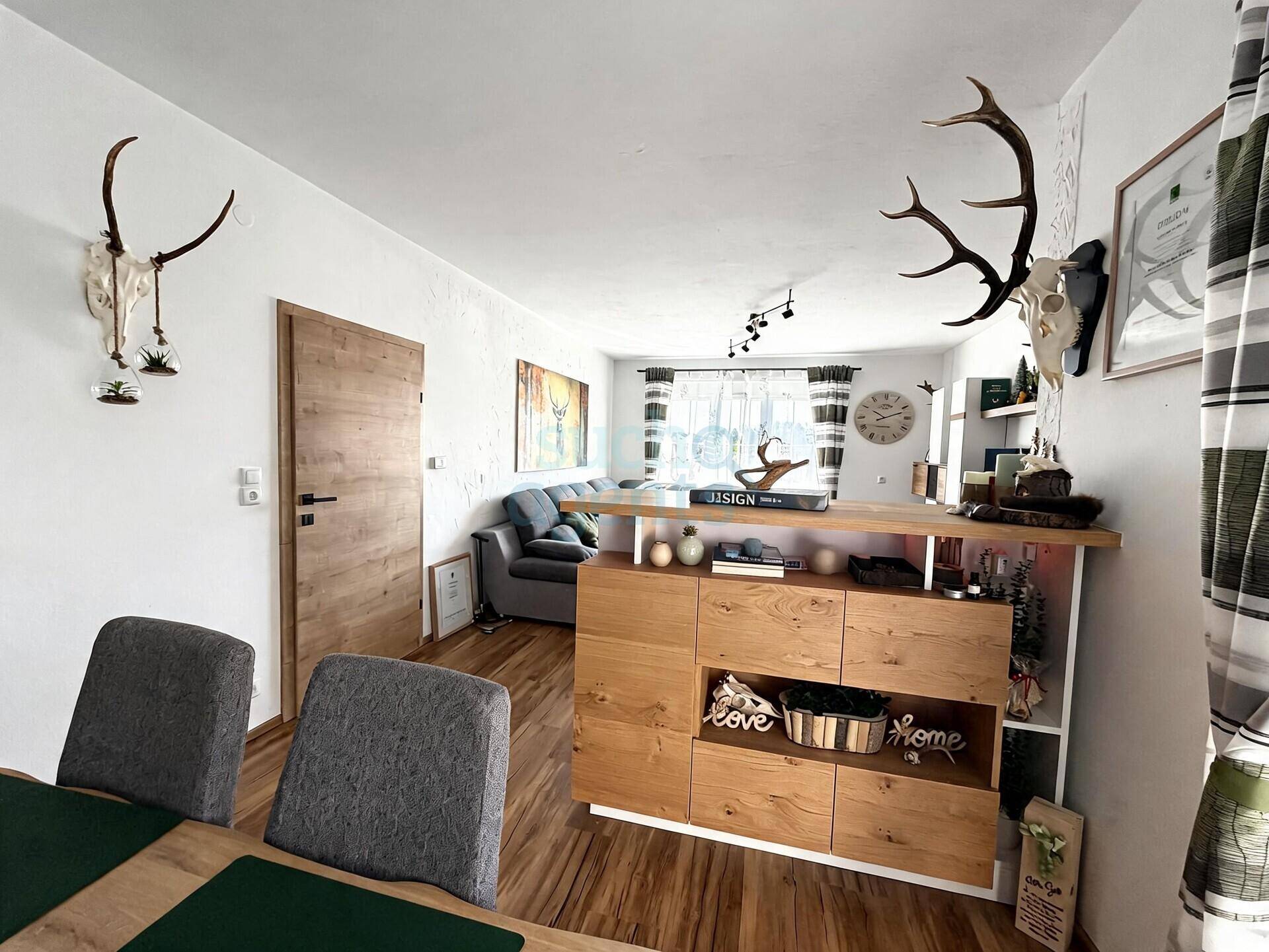 Offener Wohn- und Essbereich mit Holzboden, modernem Sideboard und rustikalen Dekorationselementen.