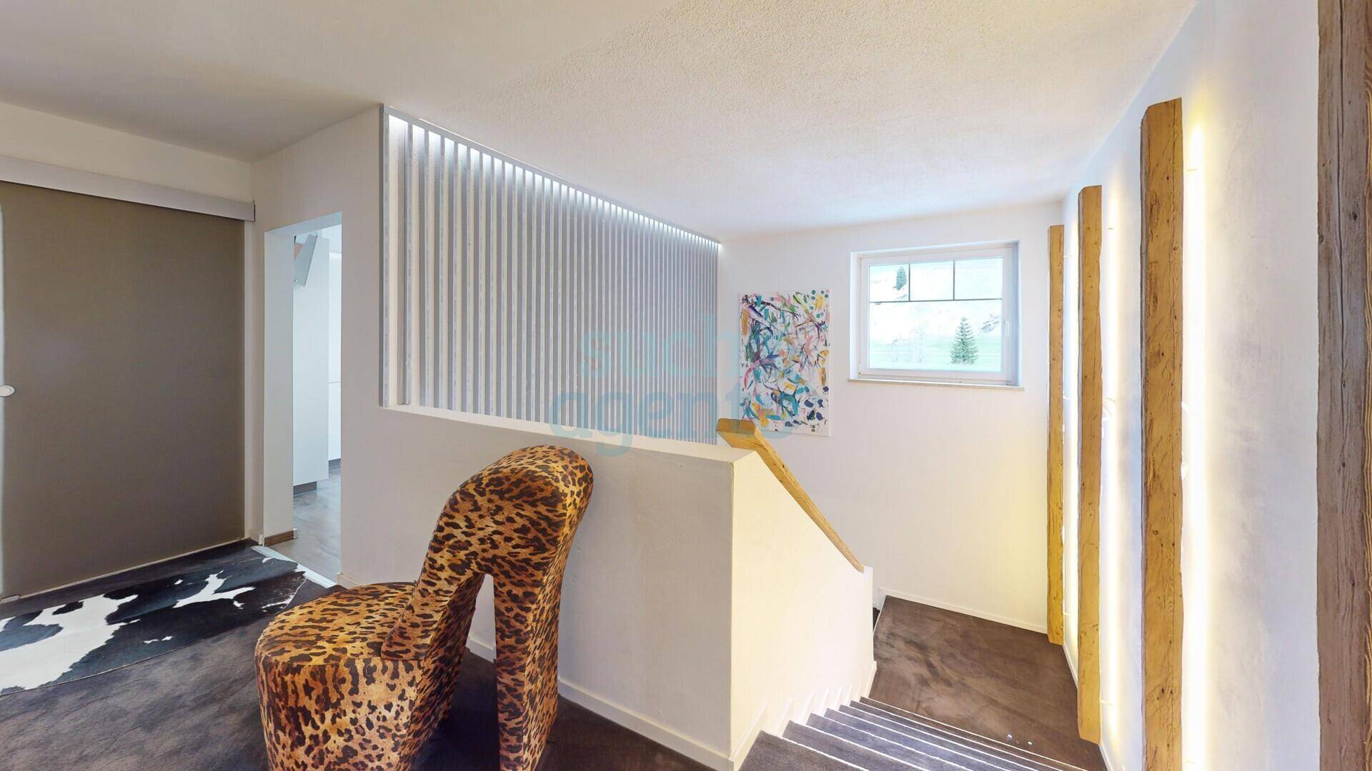 Heller Flurbereich mit Treppenaufgang, dekorativen Holzlamellen und Fenster für natürliches Licht.