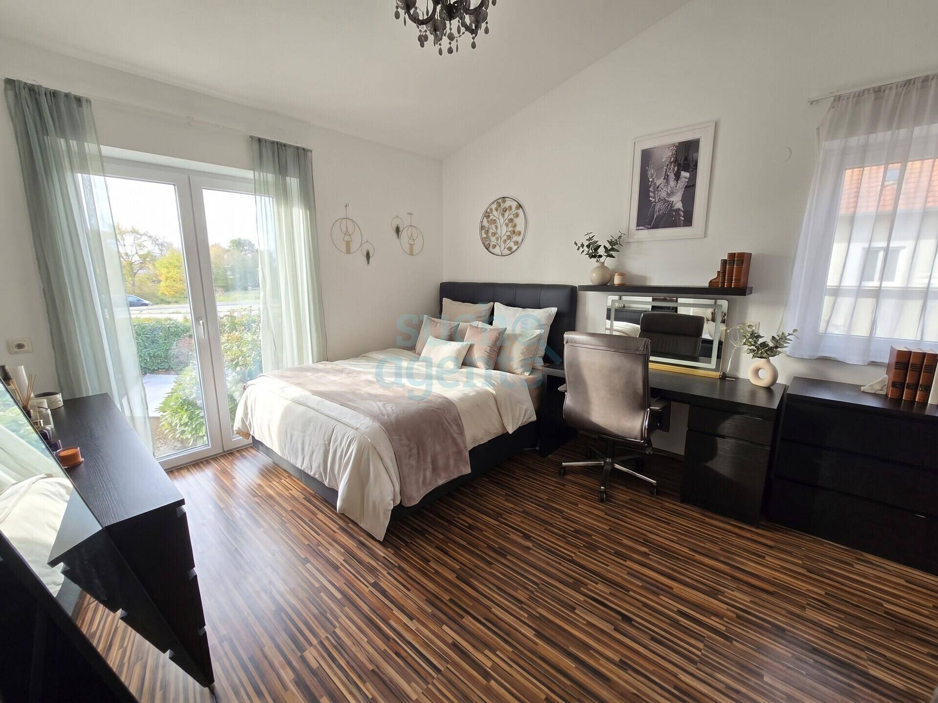 Gemütliches Schlafzimmer mit Holzboden, direktem Zugang zum Außenbereich und moderner Einrichtung.