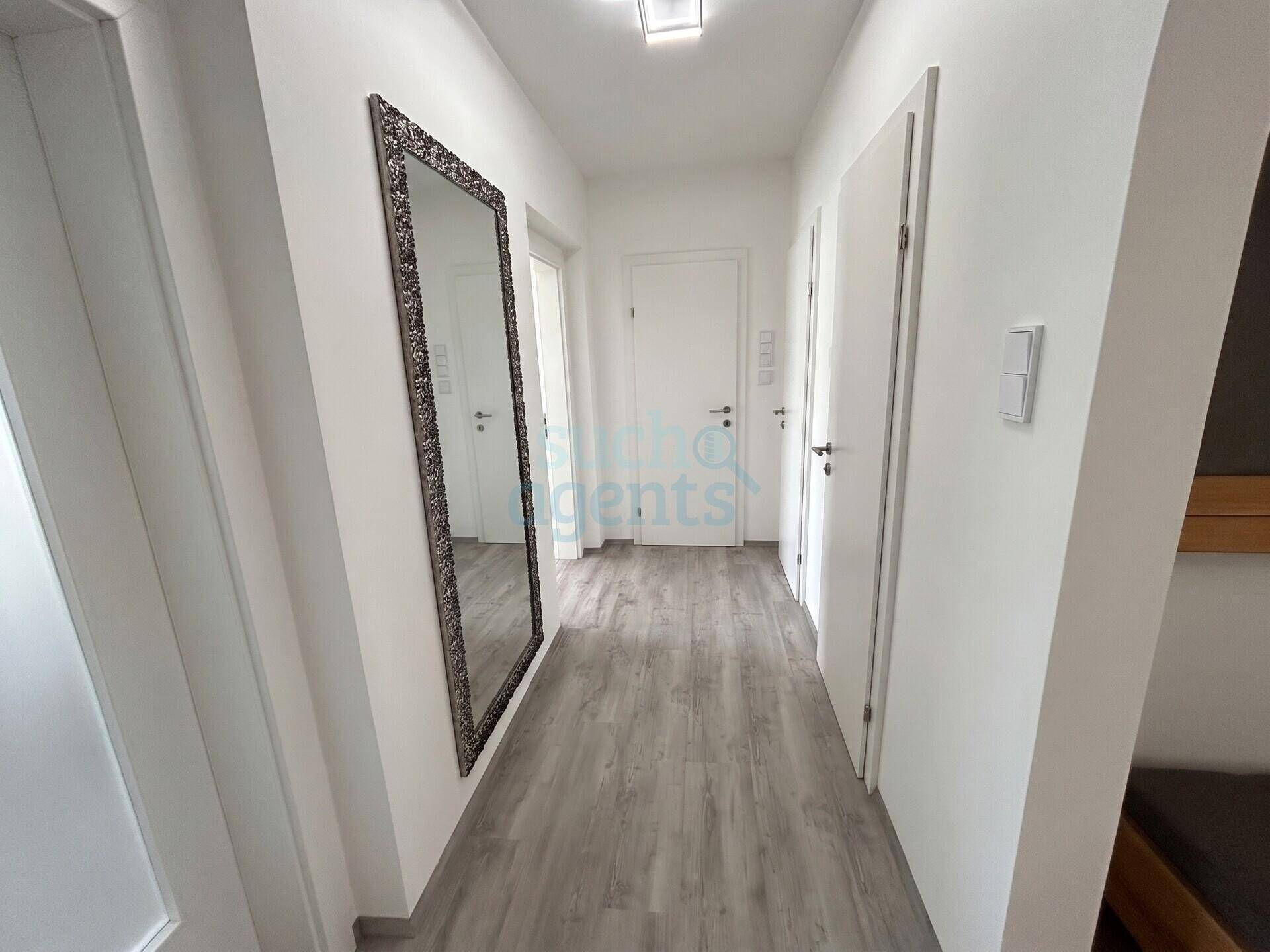 Heller Flur mit großem Spiegel und modernem Laminatboden.