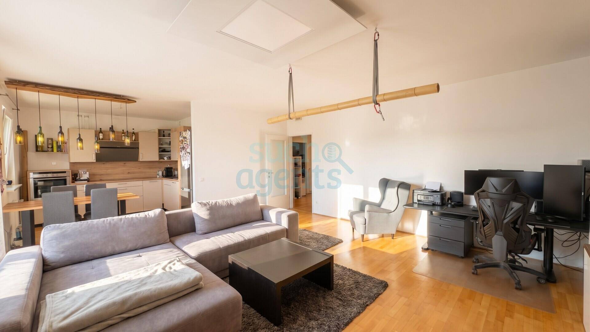Geräumiger offener Wohn-Essbereich mit Holzboden und integrierter Küche, ideal für geselliges Beisammensein.